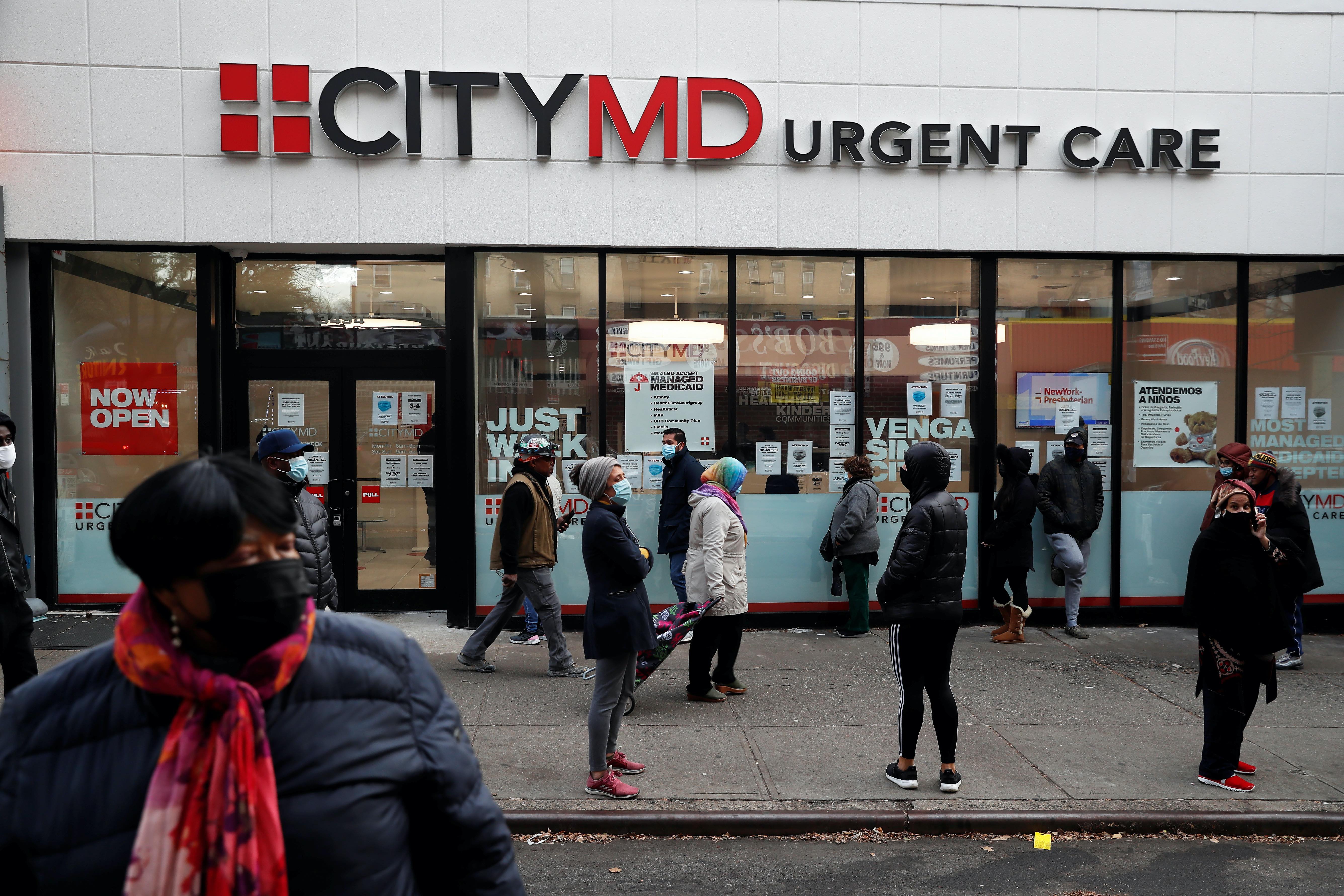 People wearing protective face masks wait in line outside a CityMD Urgent Care, as the global outbreak of the coronavirus continues, in the Bronx, New York