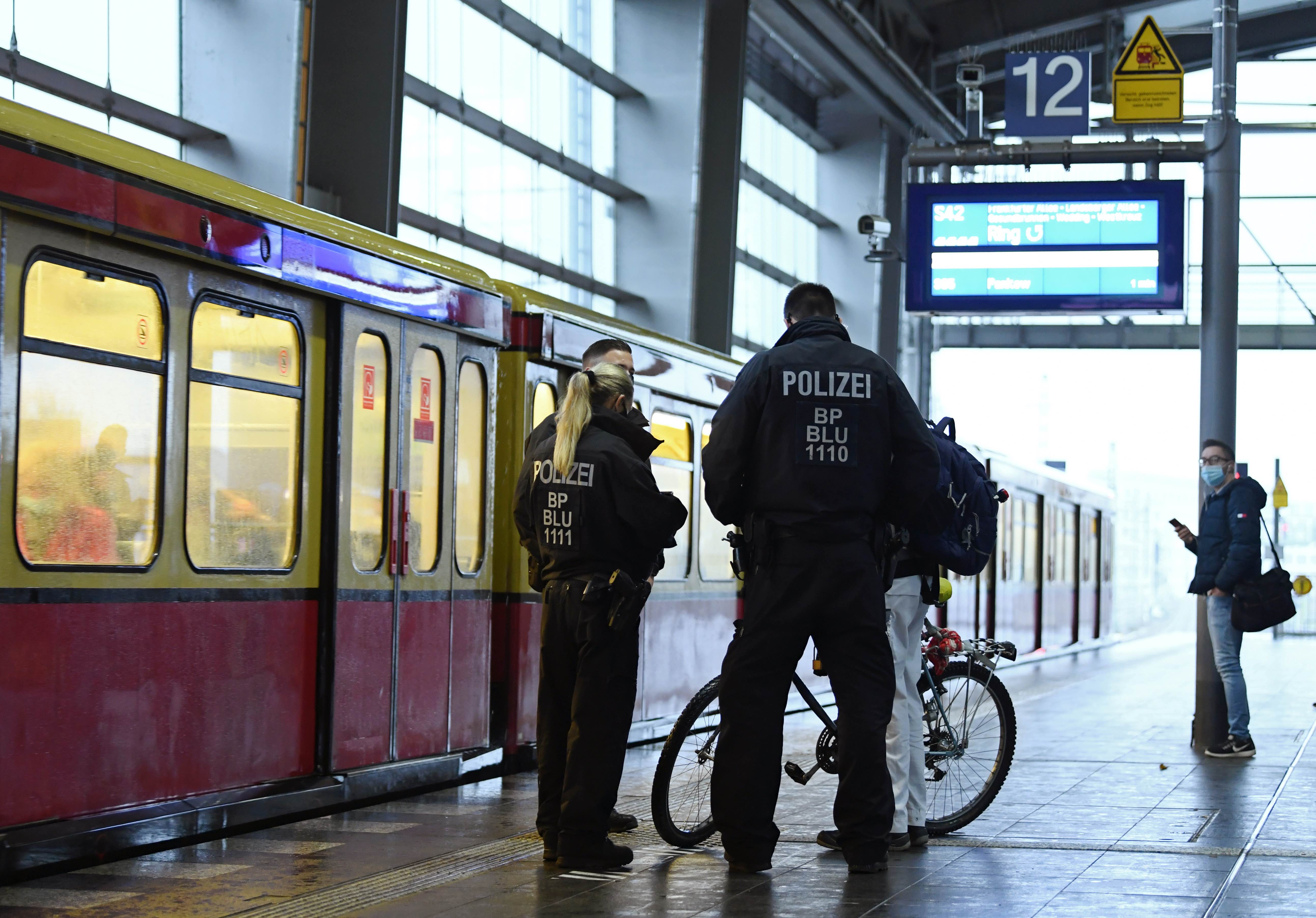 Police officers talk to a man on a railway platform while checking if people are wearing mouth and nose protection as the spread of the coronavirus continues in Berlin, Germany