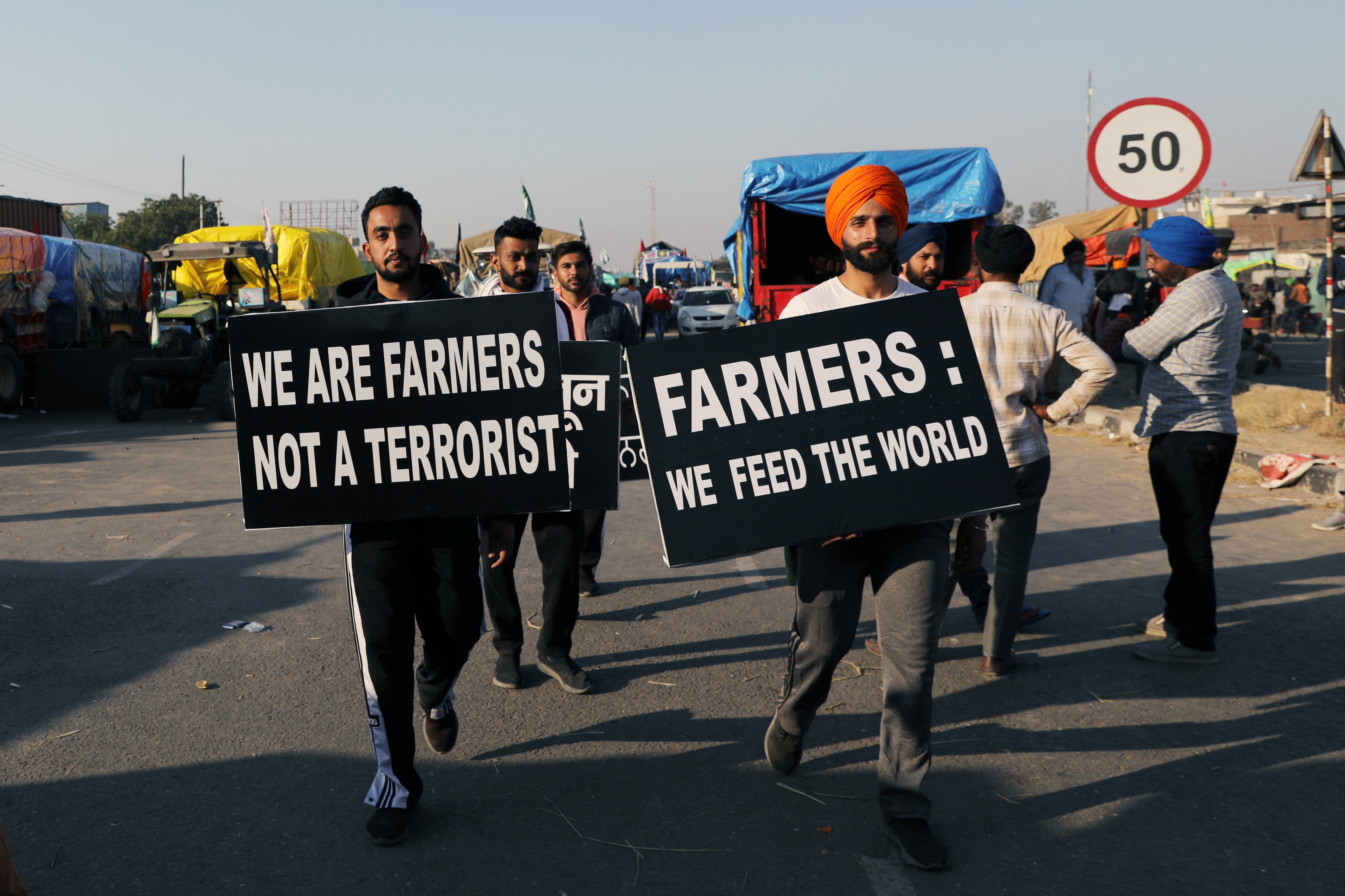 Farmers carry placards at a site of a protest at Singhu border near New Delhi
