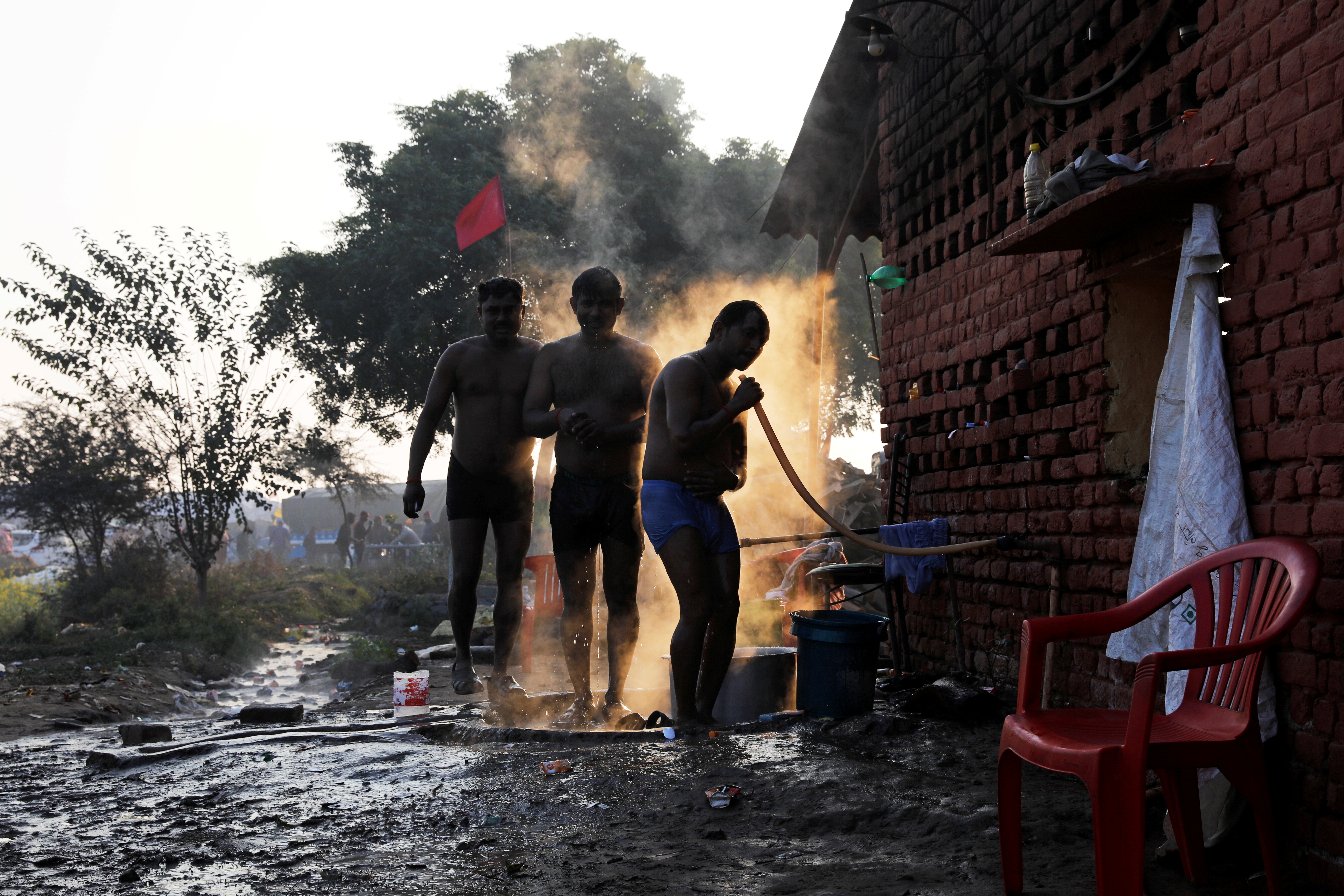 Farmers wash themselves at the site of a protest against new laws, at a national highway in Rajasthan state’s Shahjahanpur, near New Delhi