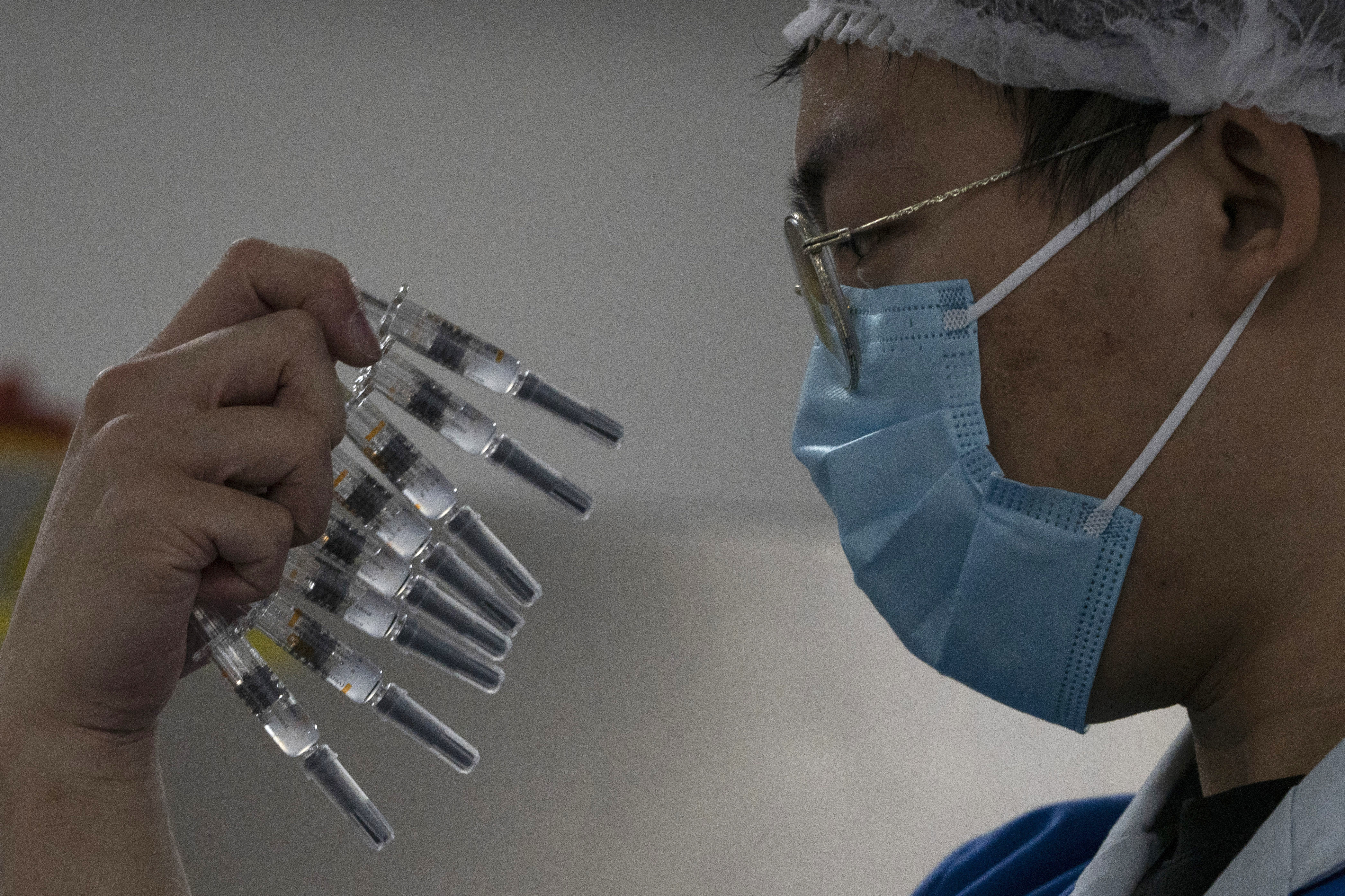 A worker inspects syringes of a vaccine for COVID-19 produced by Sinovac