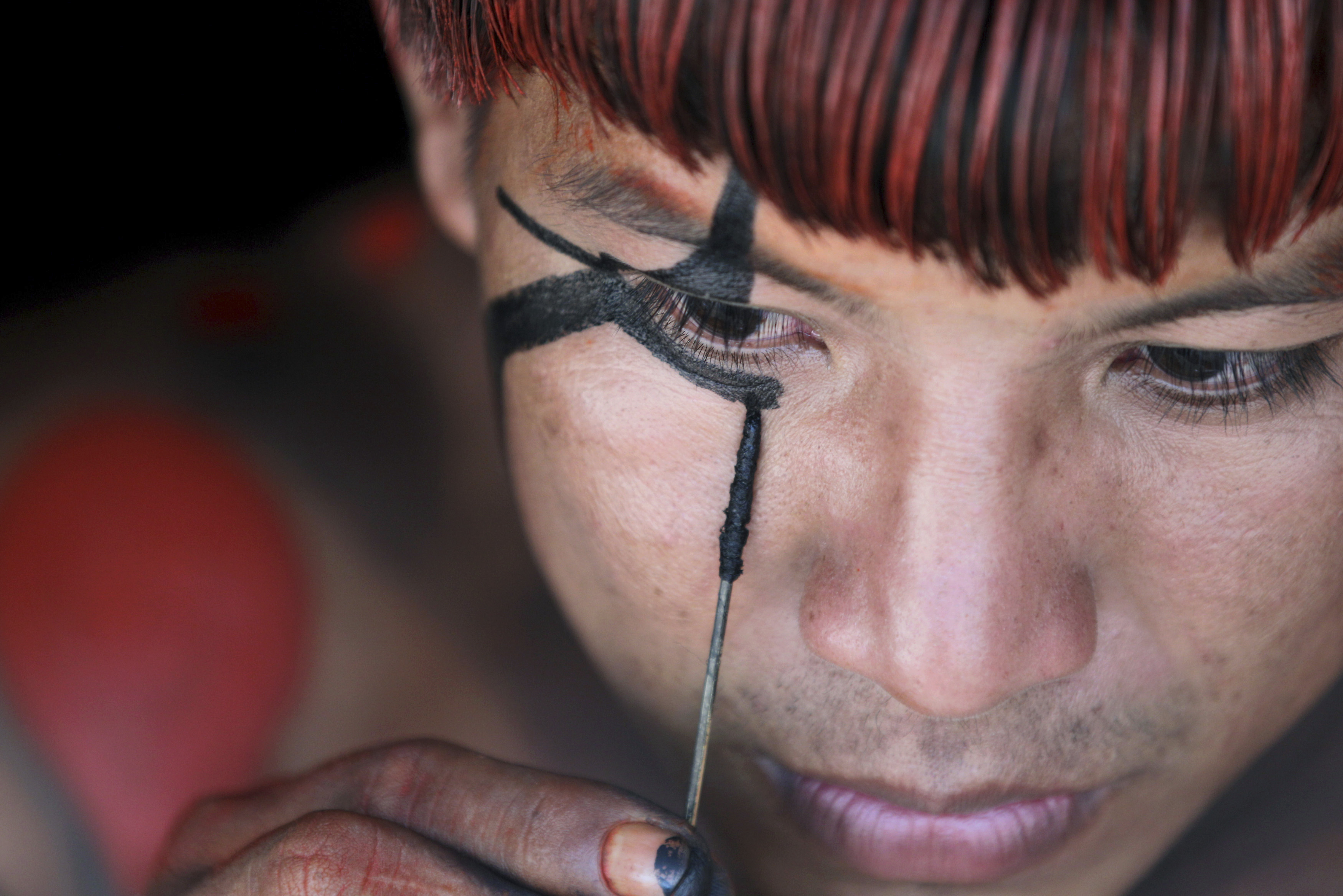A Yawalapiti man paints his face to prepare for a ‘quarup’ ritual held over several days to honour in death a person of great importance, in the Xingu National Park