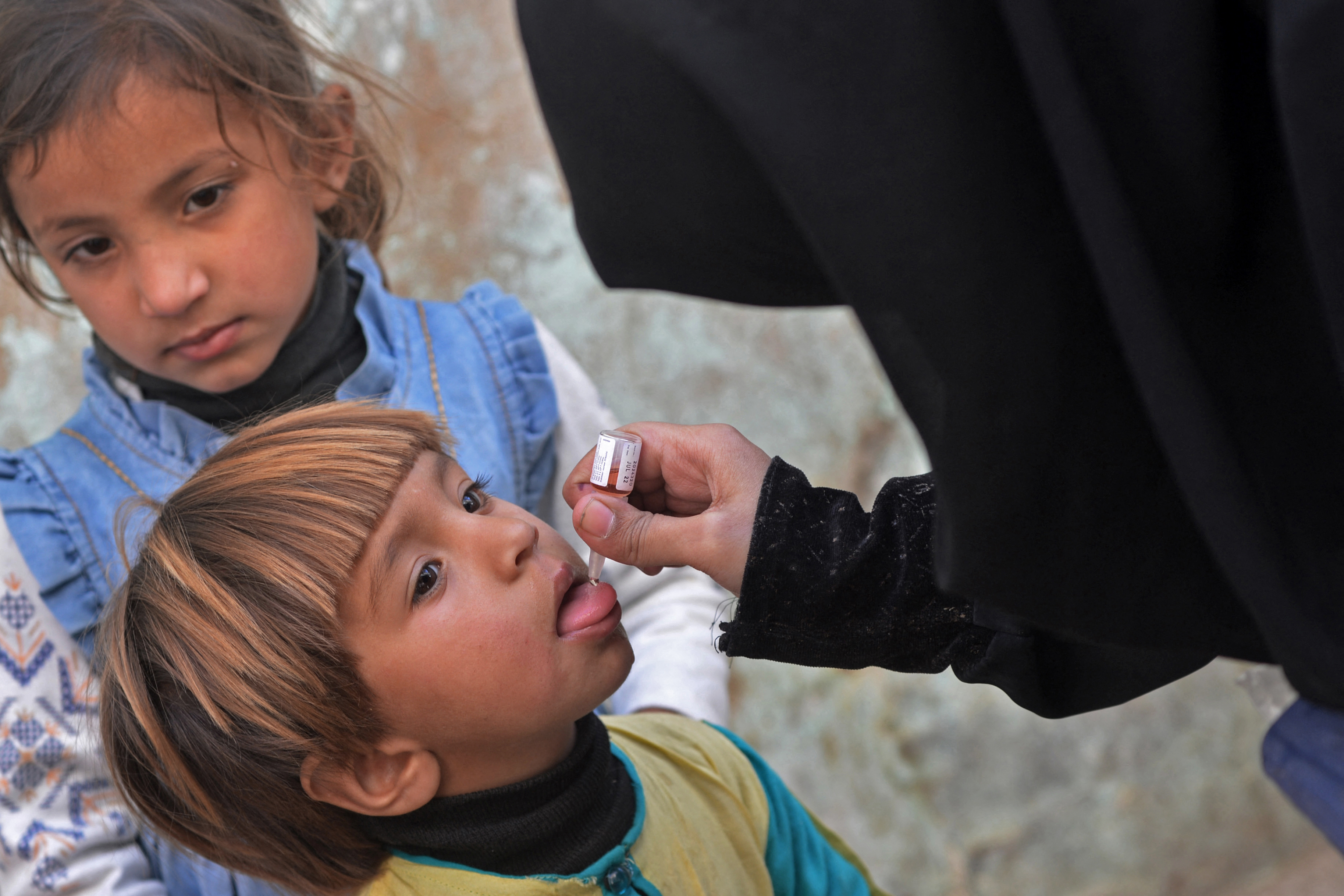 A health worker administers polio vaccine drops to a child during a door-to-door polio vaccination campaign in Karachi on January 11, 2021