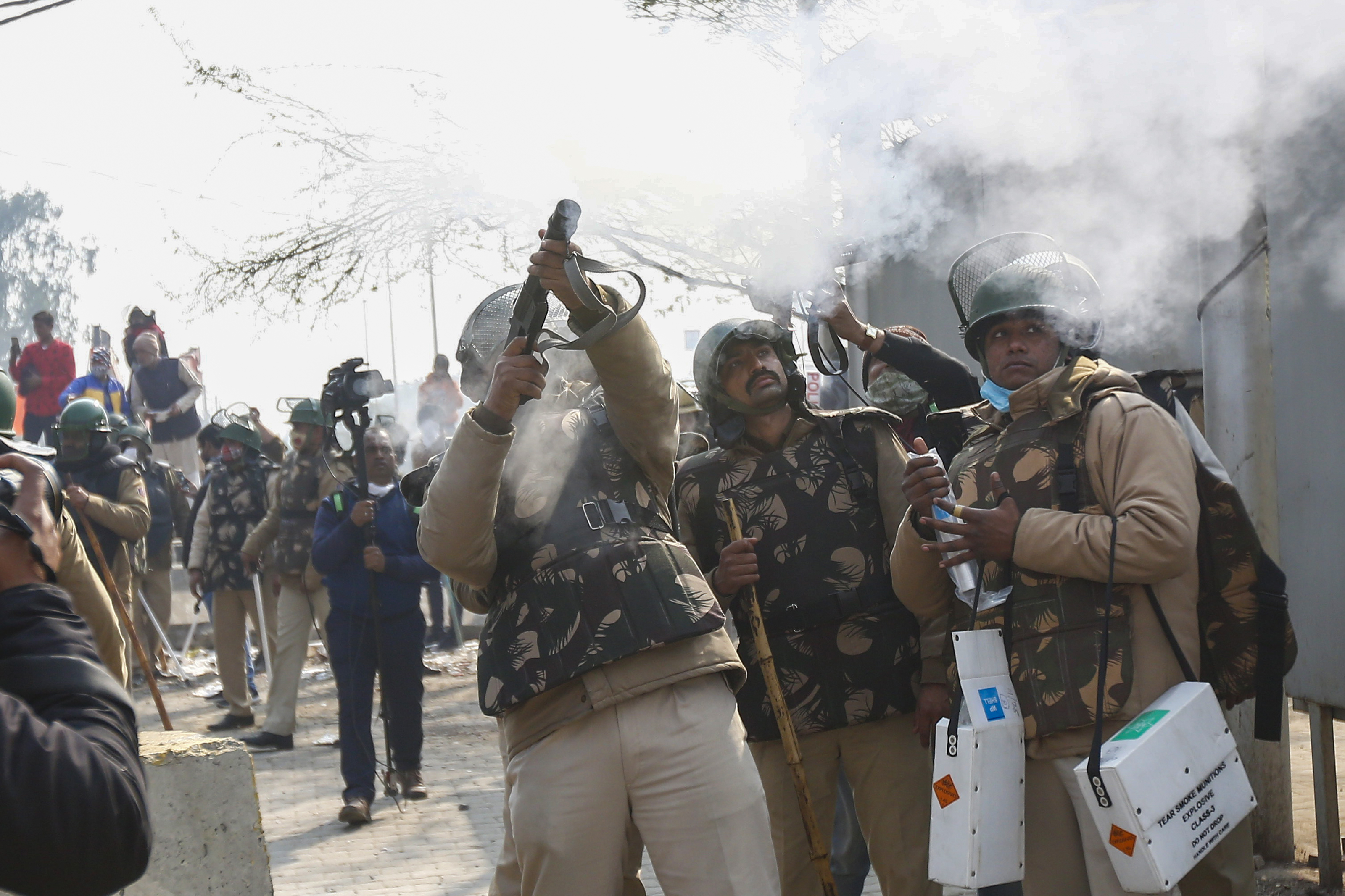 Security personnel fire a tear gas shell during clashes between farmers and their opponents