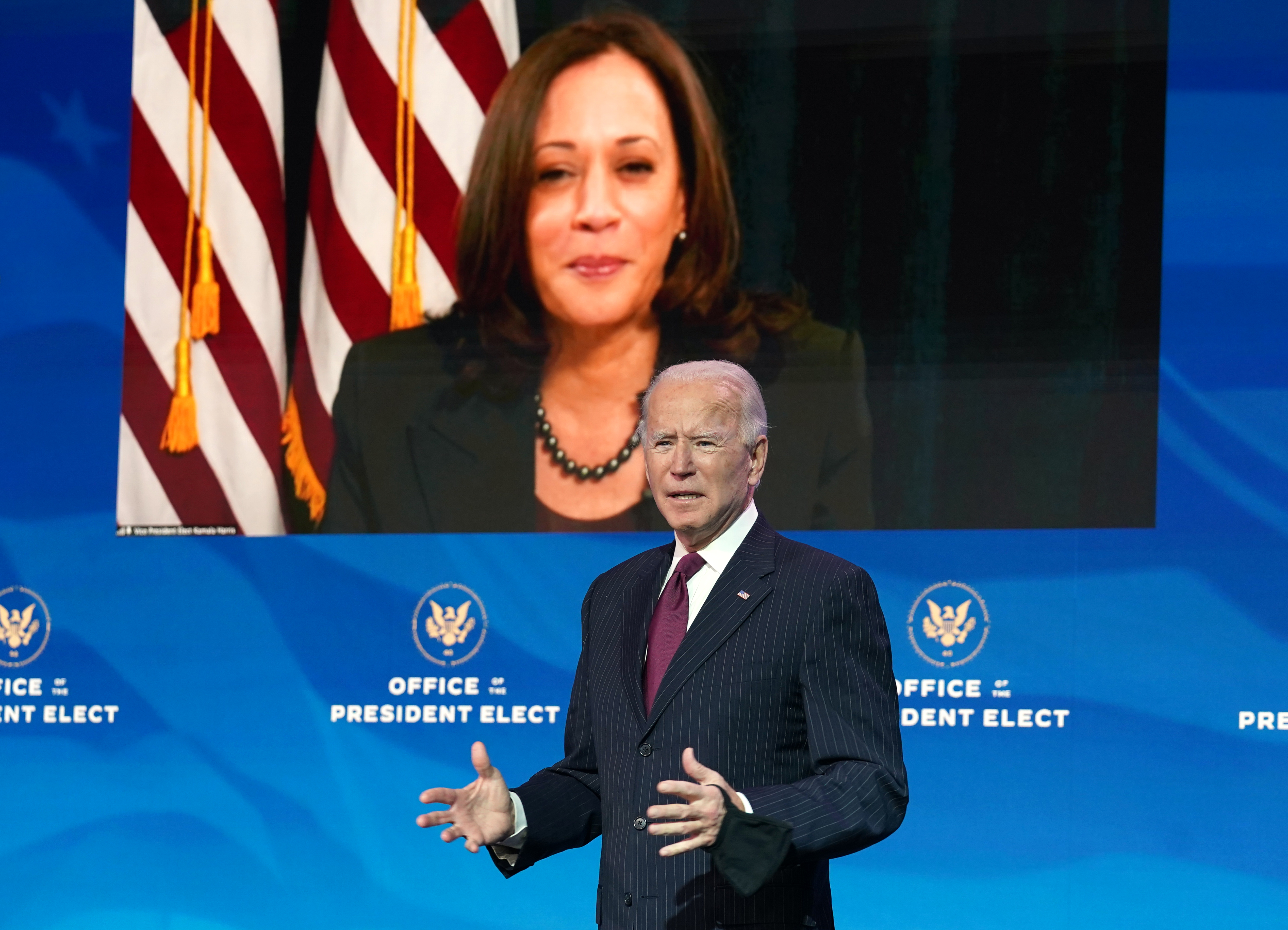 Vice President-elect Kamala Harris, appearing via video link, listens as President-elect Joe Biden speaks during a news conference at his transition headquarters