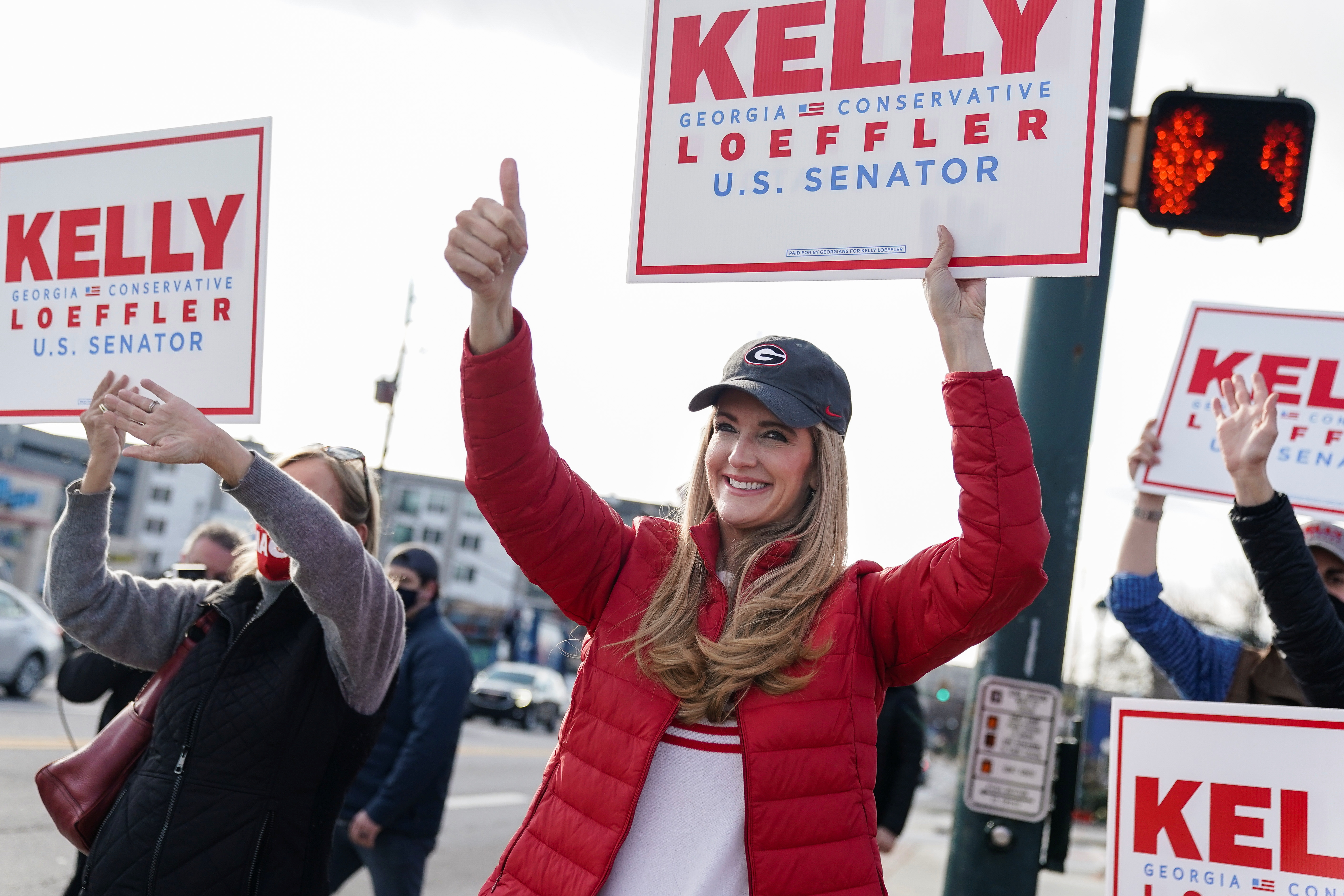 Republican US Senator Kelly Loeffler waves a campaign sign with supporters outside Sandy Springs City Hall in Sandy Springs, Georgia, January 5, 2021