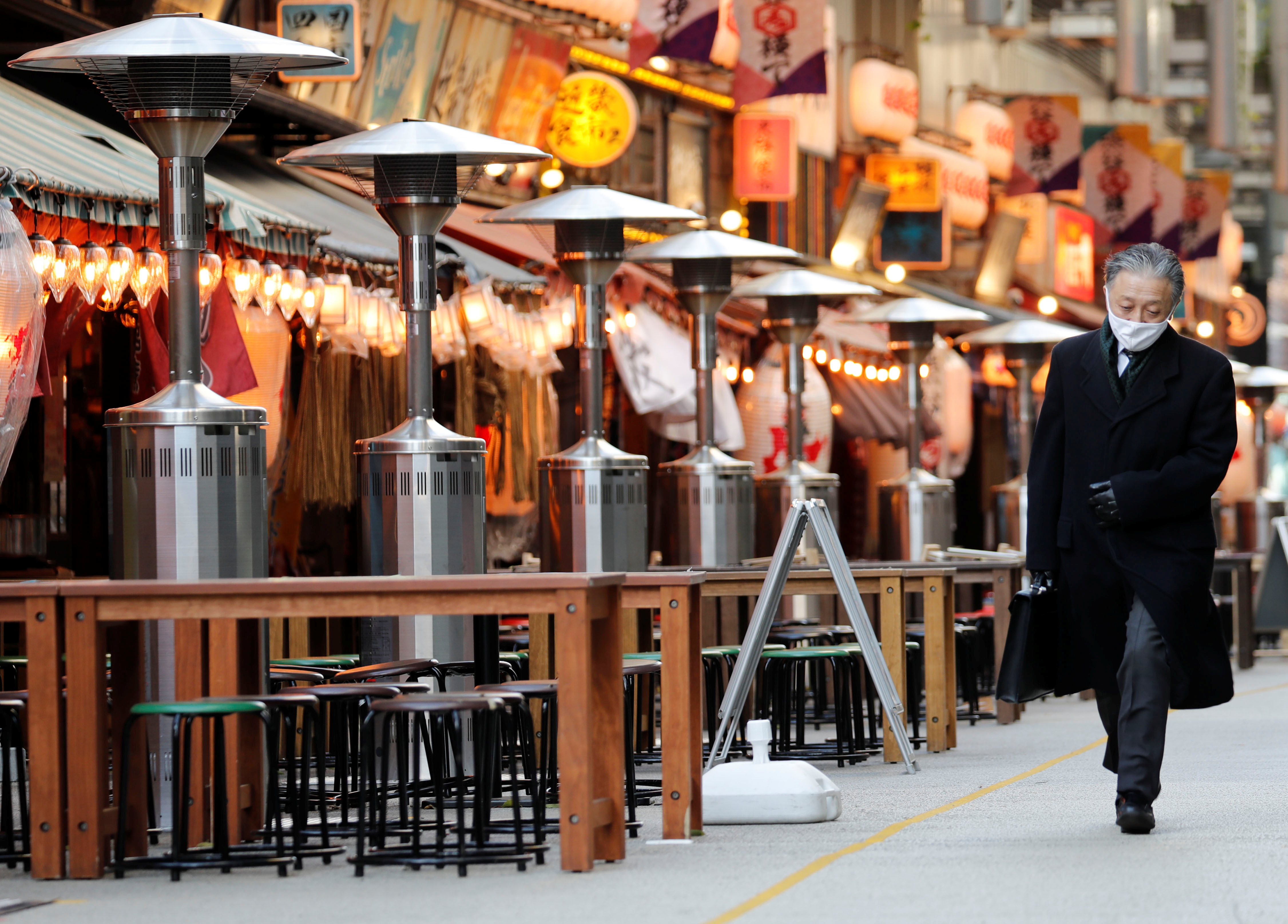 A man, wearing a protective mask against COVID-19, walks past empty tables at a restaurant in Tokyo, Japan, January 7, 2021