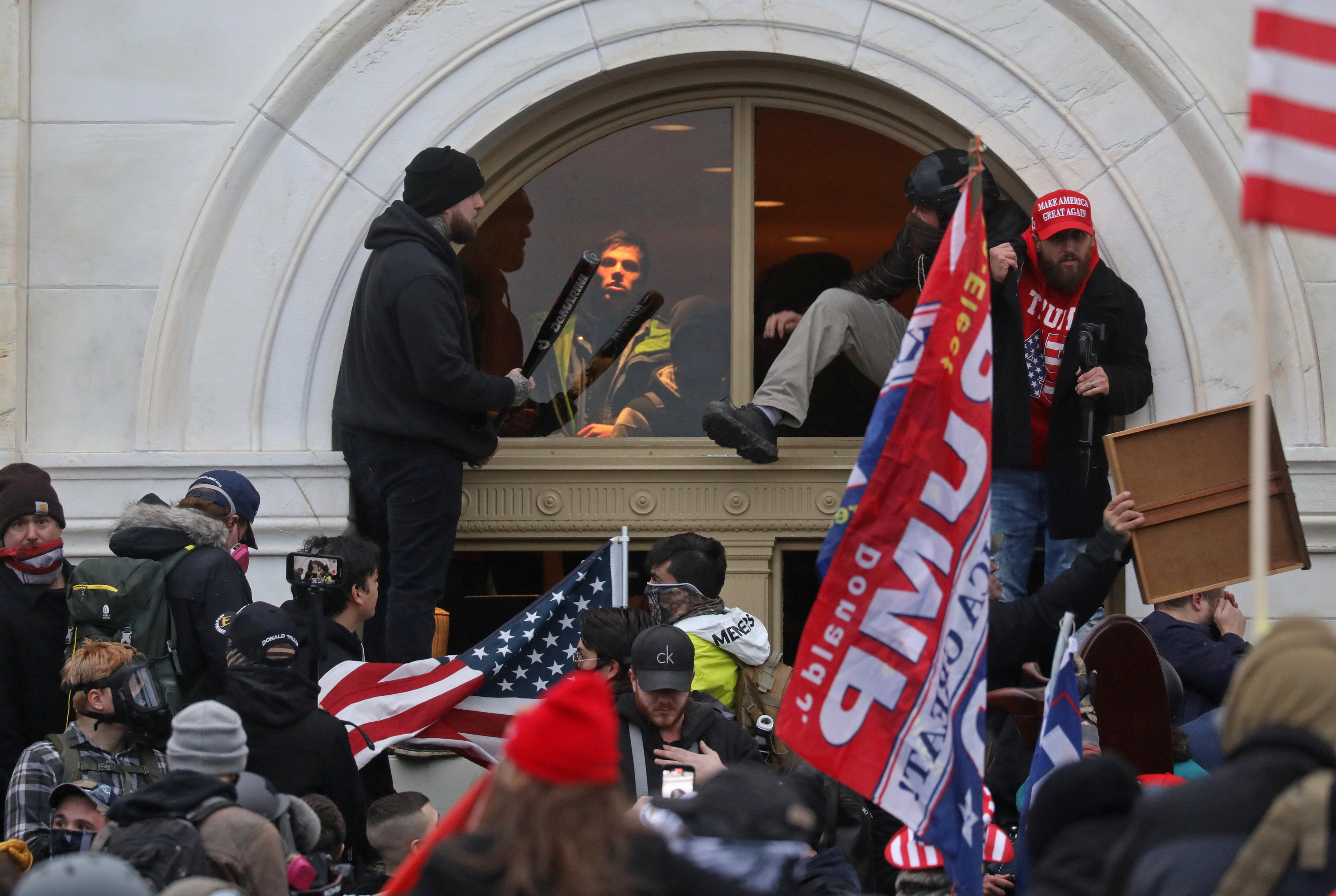 A mob of supporters of US President Donald Trump climb through a window they broke as they storm the US Capitol Building in Washington, DC, January 6, 2021
