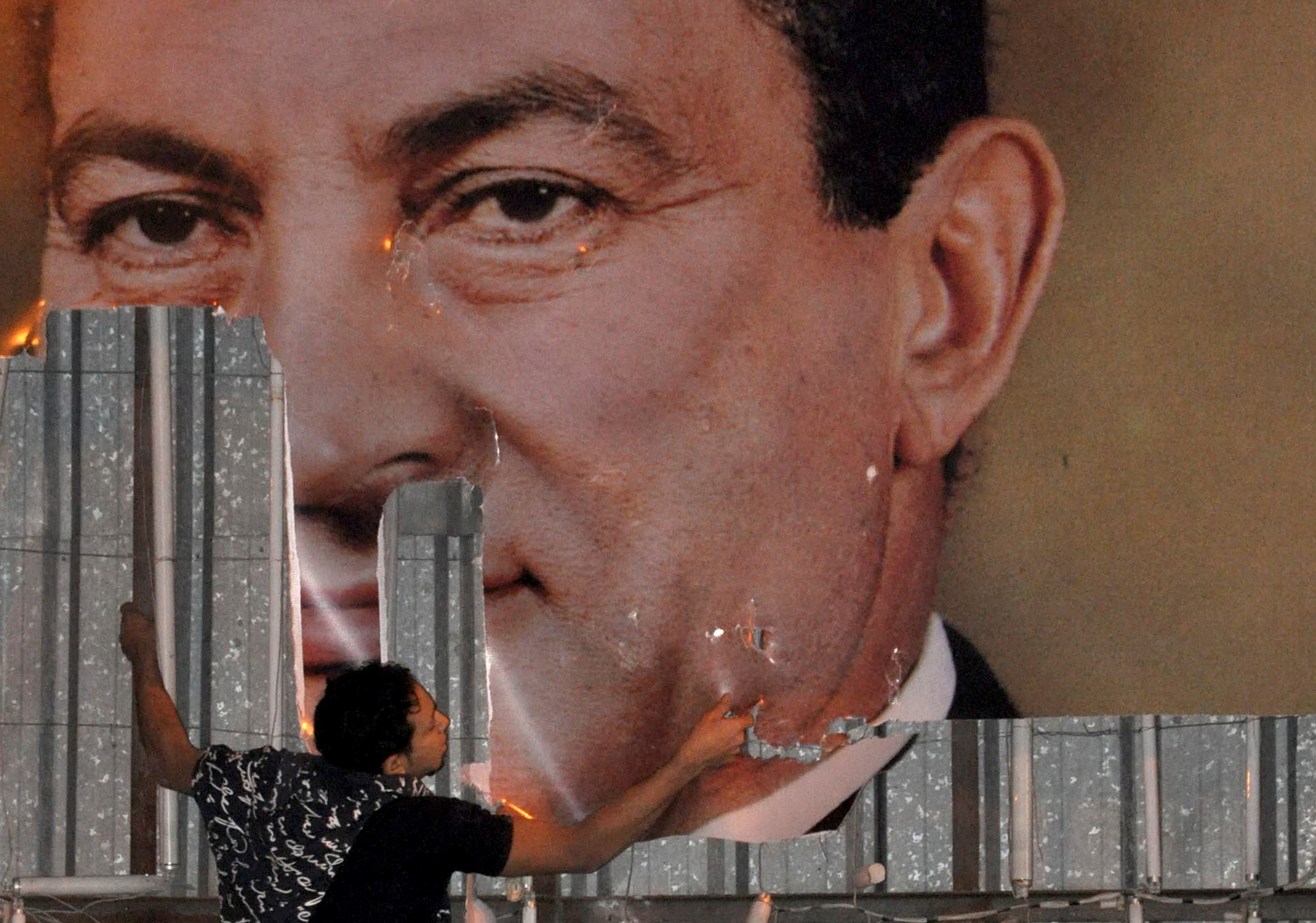 An anti-government protester defaces a picture of Egypt's President Hosni Mubarak in Alexandria on January 25, 2011 [File: Reuters/Stringer]