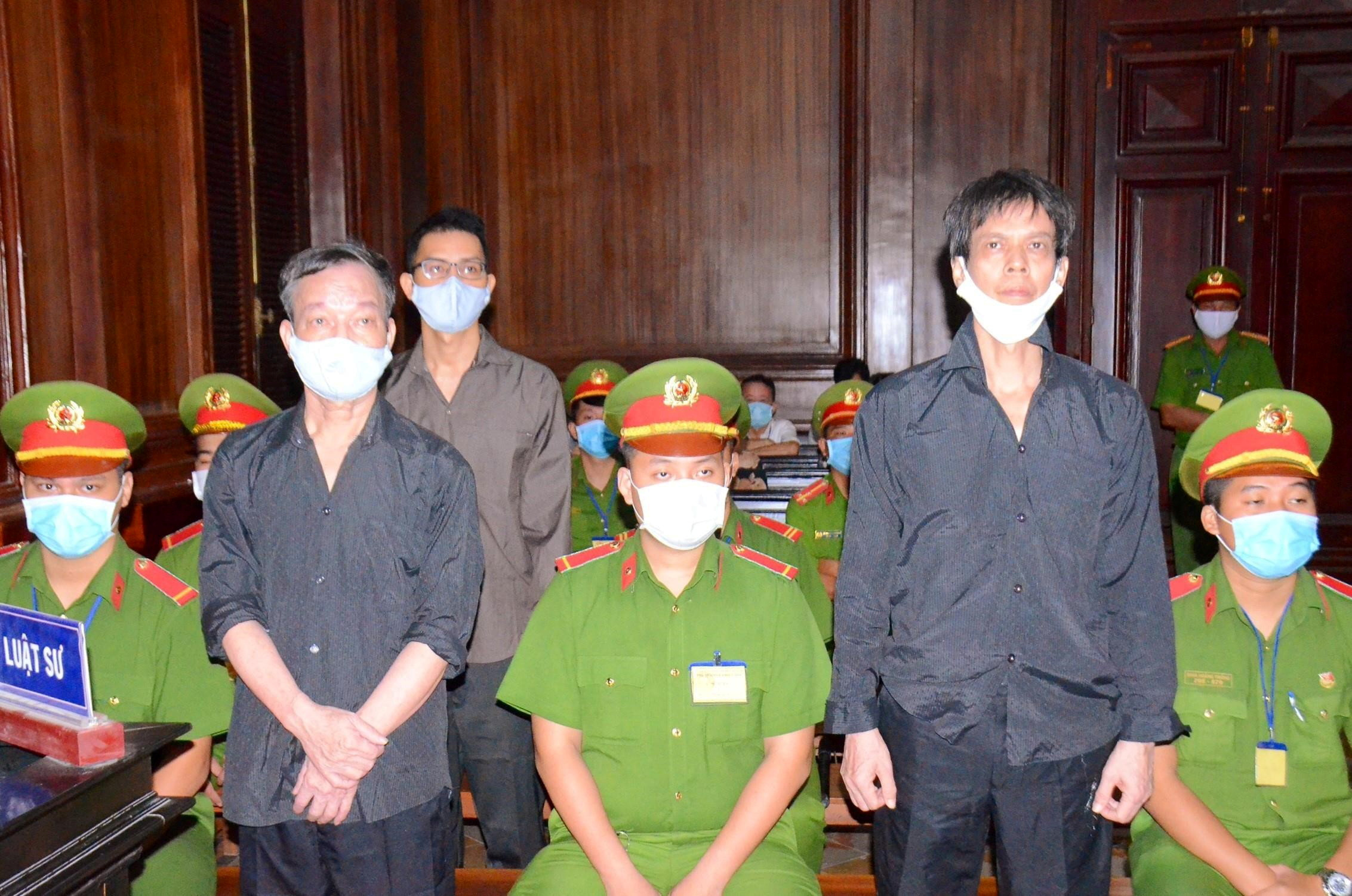 Journalists Pham Chi Dung, right, Le Huu Minh Tuan, centre, and Nguyen Tuong Thuy, left, stand between police during their trial at a court in Ho Chi Minh City, Vietnam January 5, 2021