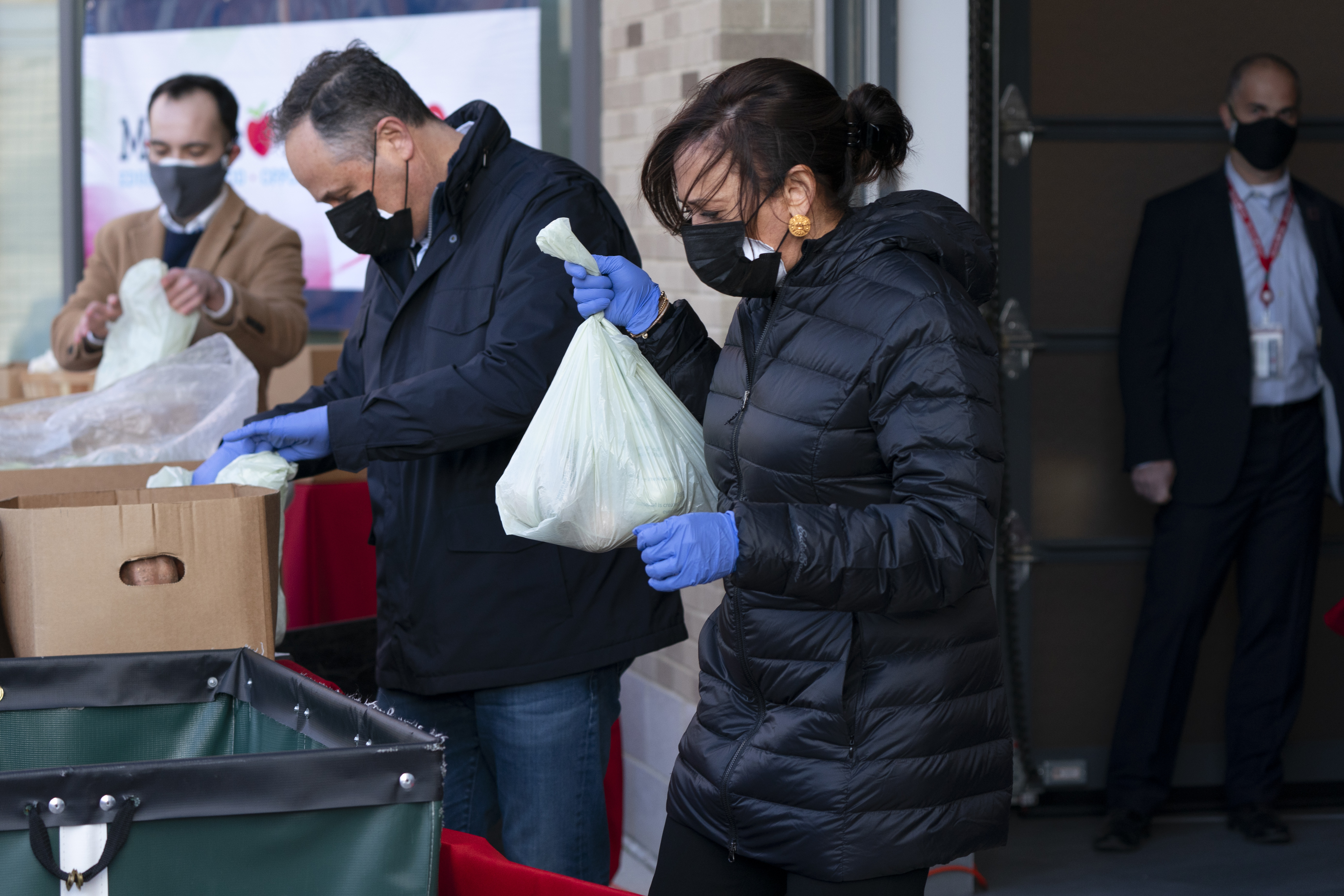 Vice President-elect Kamala Harris, centre, and her husband Douglas Emhoff, centre left, pack grocery bags for those in need of food while volunteering during the National Day of Service, on Monday at Martha’s Table in southeast Washington, DC