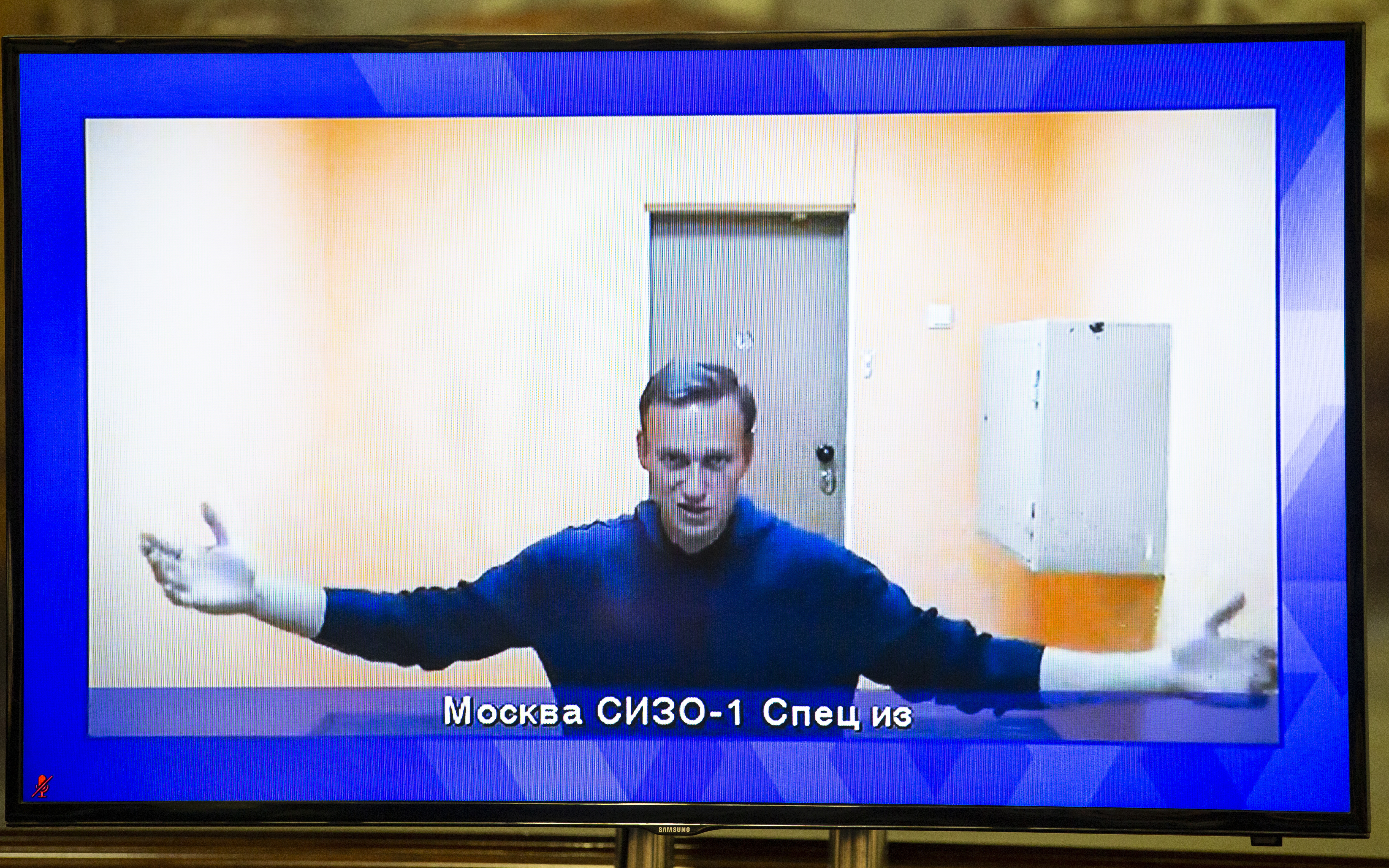 Russian opposition leader Alexei Navalny appears on a TV screen during a live session with the court during a hearing of his appeal in a court in Moscow, Russia