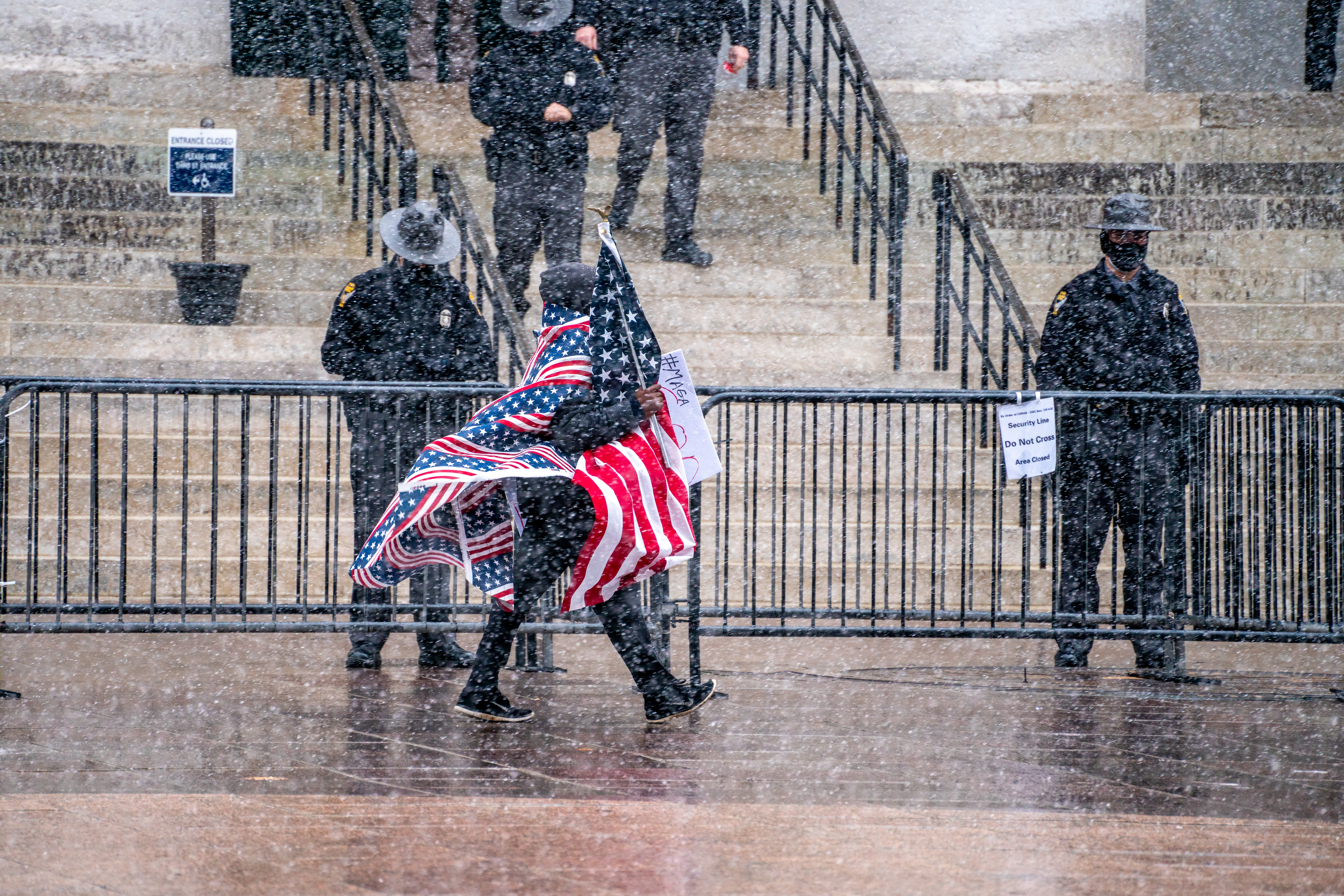 A man wrapped in US flags paces back and forth past Ohio State Patrol officers standing guard during an armed protest at the Ohio Statehouse in Columbus ahead of the inauguration of President-elect Joe Biden, on January 17, 2021