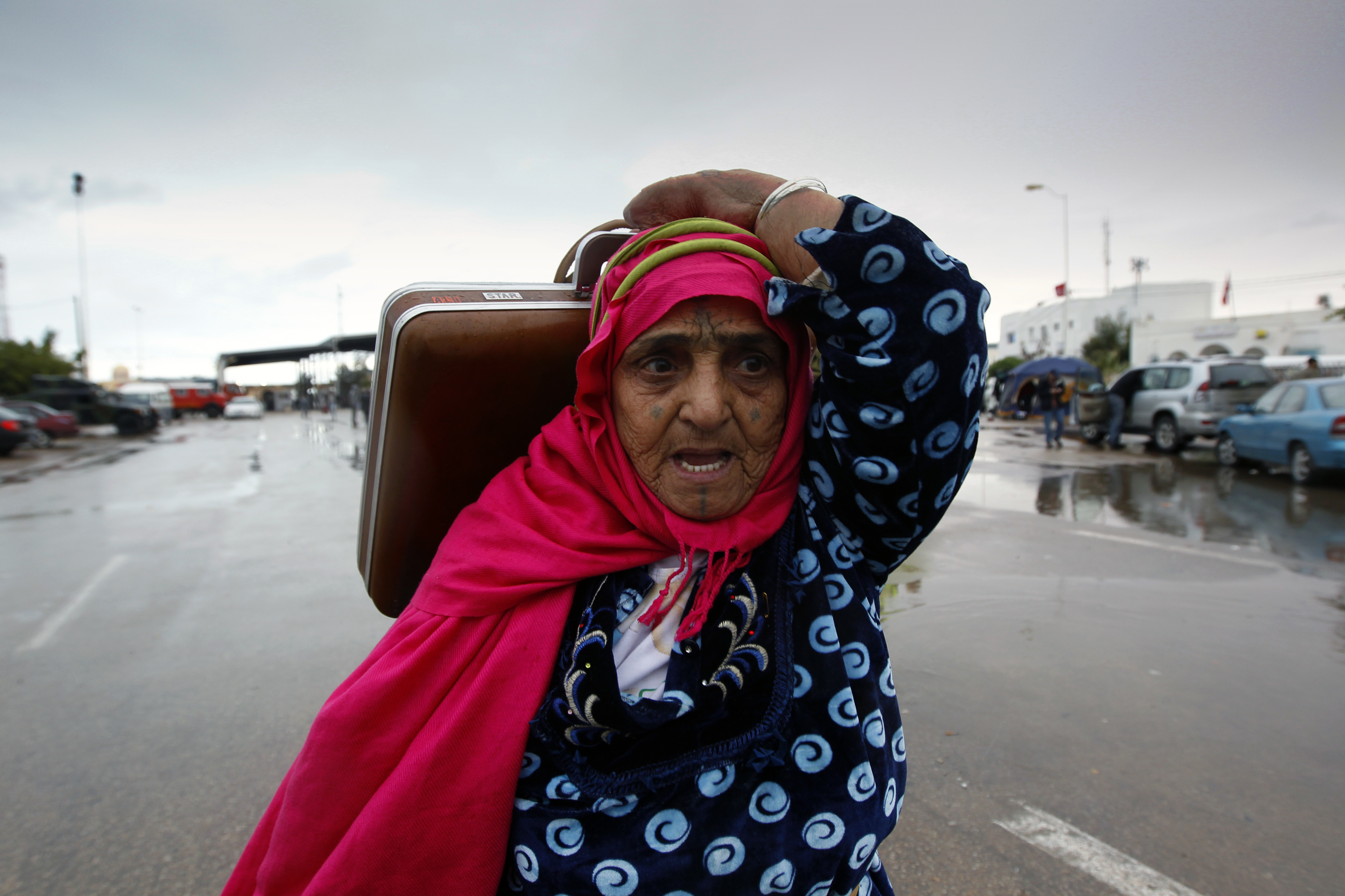 A Tunisian woman carries her belongings as she crosses into Tunisia at the Ras Jdir border crossing after fleeing unrest in Libya in 2011