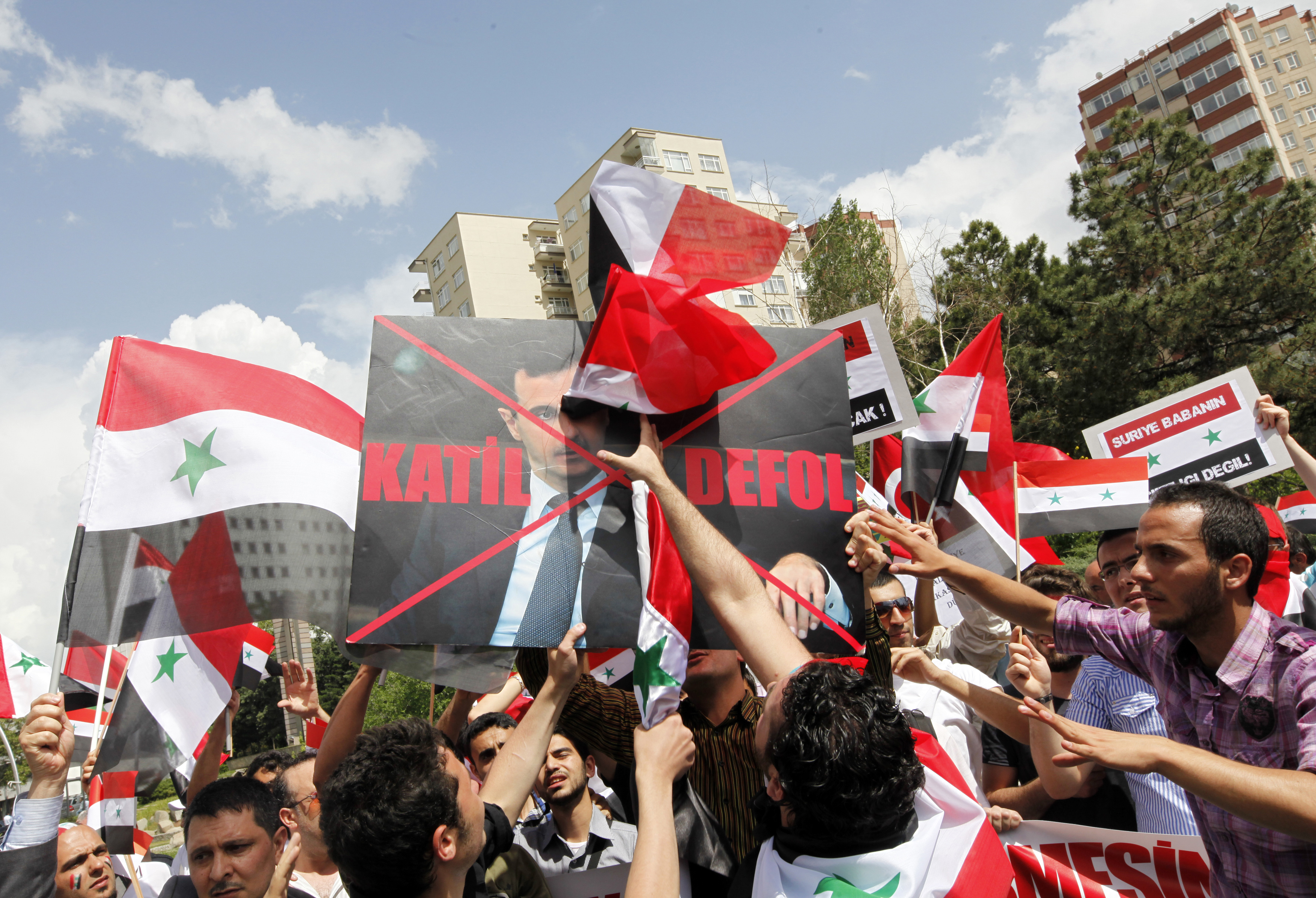 Protesters use their shoes to hit a defaced poster of Syria’s President Bashar Al-Assad, which reads ‘Murderer. Go away’, during a demonstration to express solidarity with Syria’s anti-government protesters in front of the Syrian embassy in Ankara, Turkey in 2011