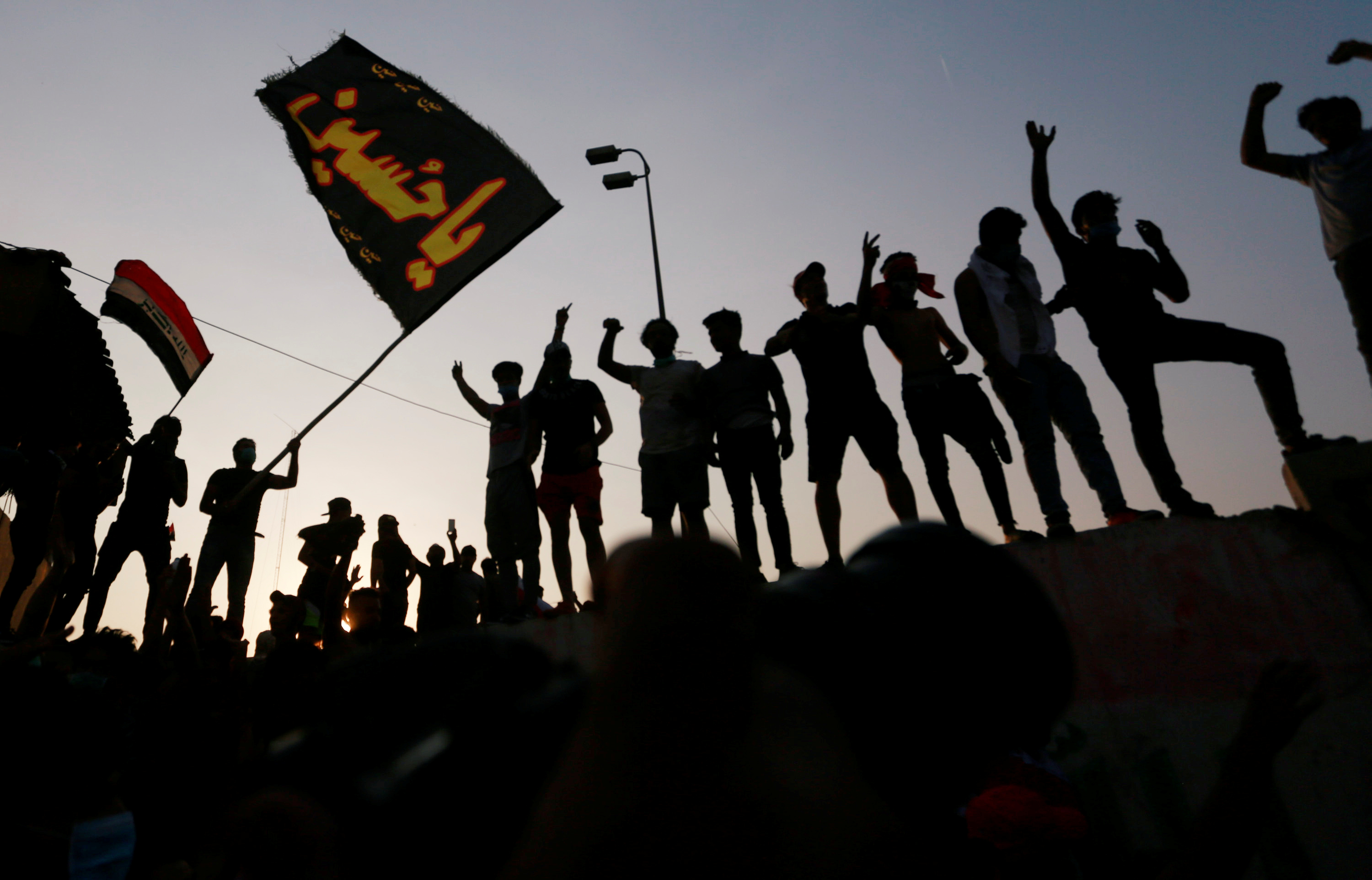 Iraqi protesters stand on concrete blast walls during a protest near the building of the government office in Basra, Iraq in September 2018