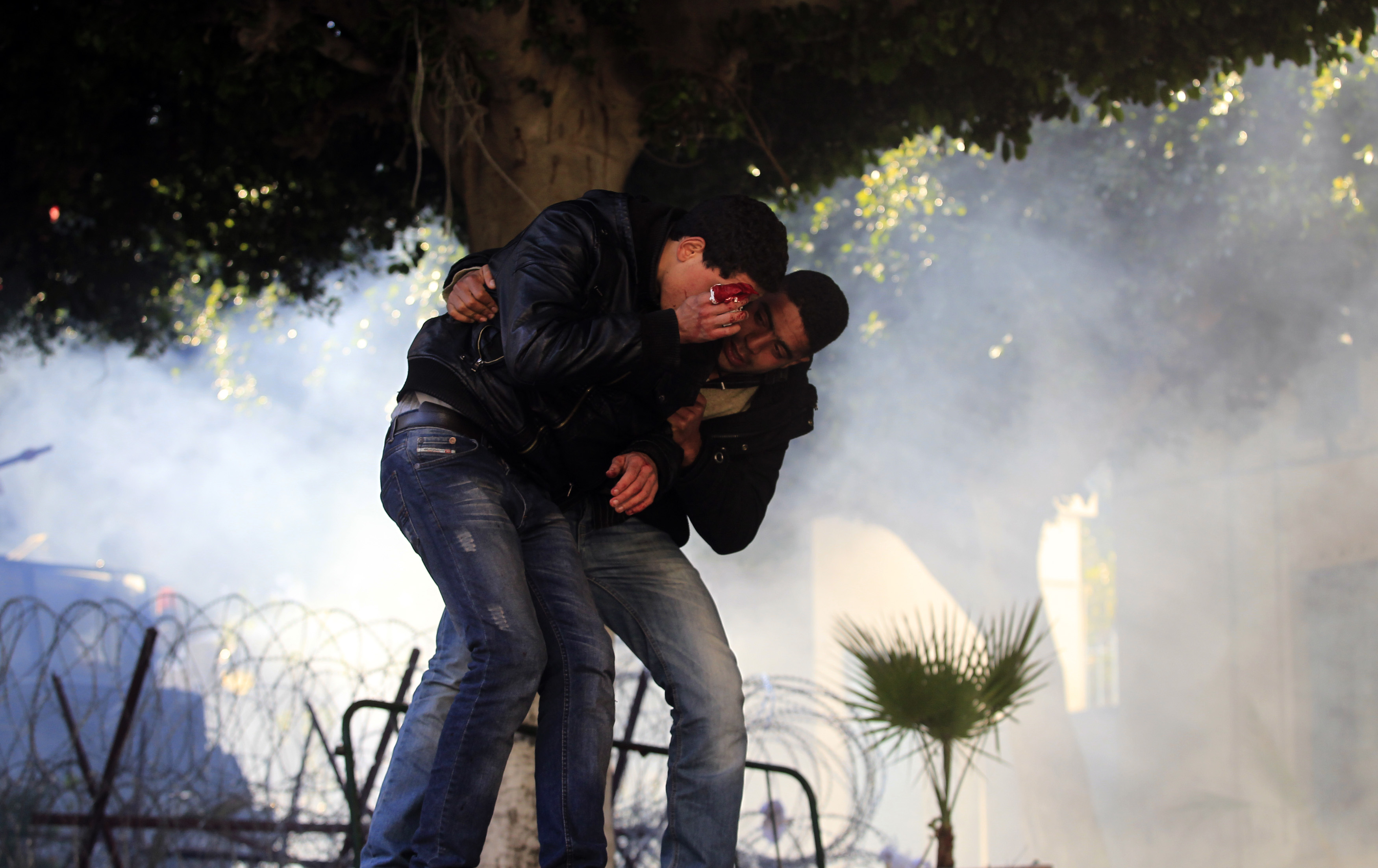 A Tunisian protester helps an injured man during clashes near government offices in the Casbah, the old city of Tunis in January 2011