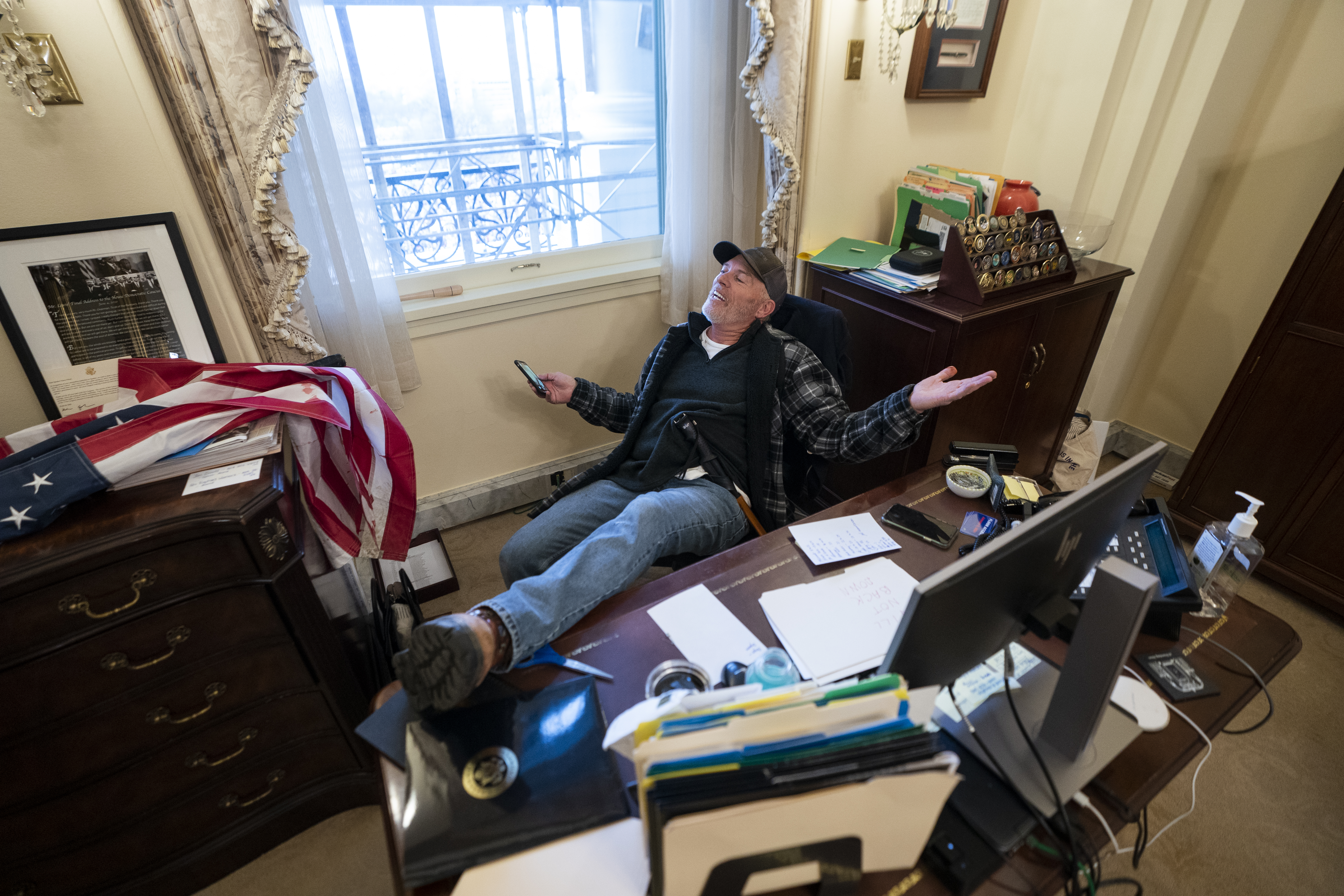 A supporter of US President Donald Trump sits at the desk of US House Speaker Nancy Pelosi after Trump supporters breached the US Capitol building
