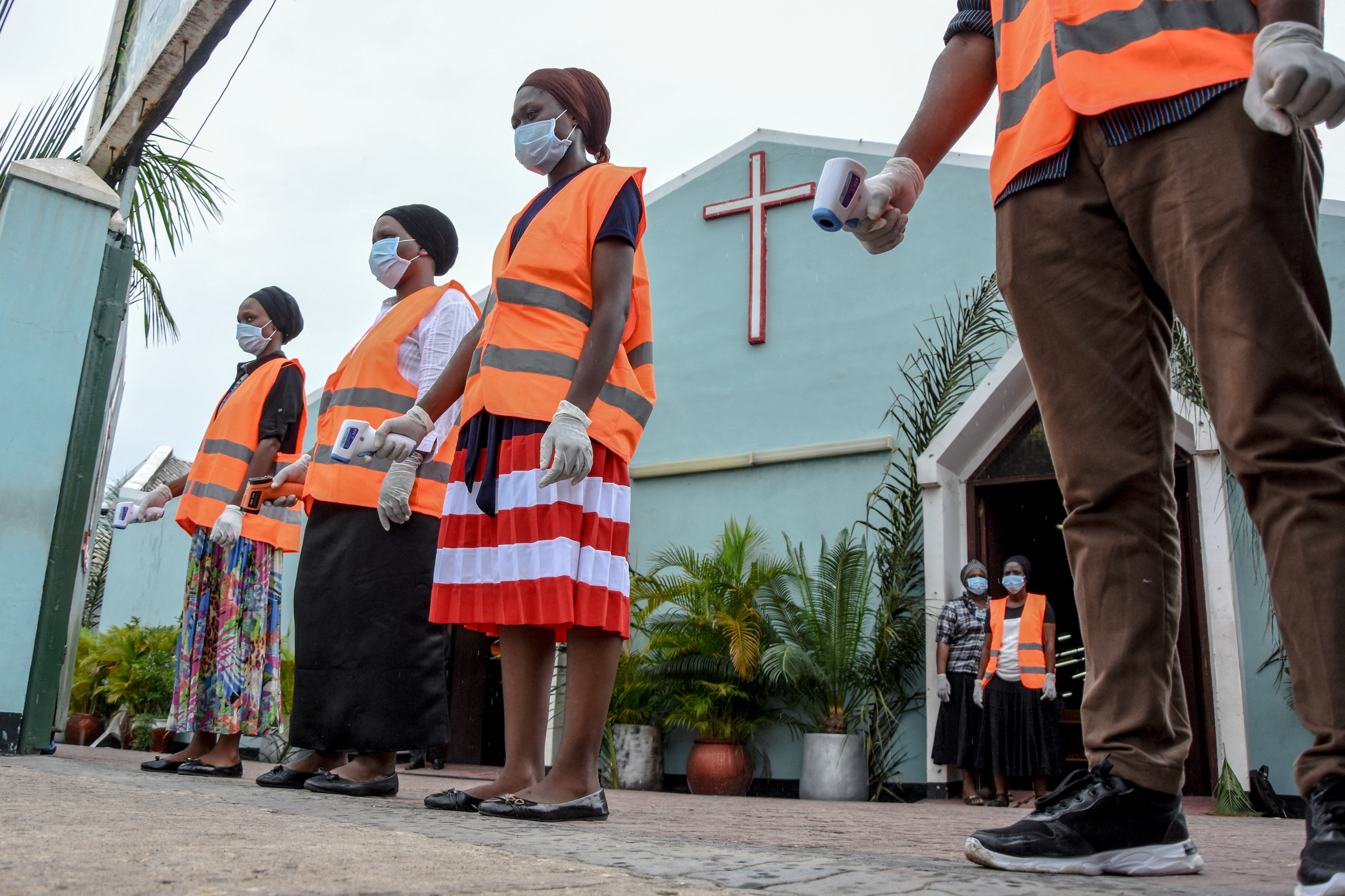 Church members wait for worshippers to take their temperature during a Palm Sunday mass in Dar-es-Salaam