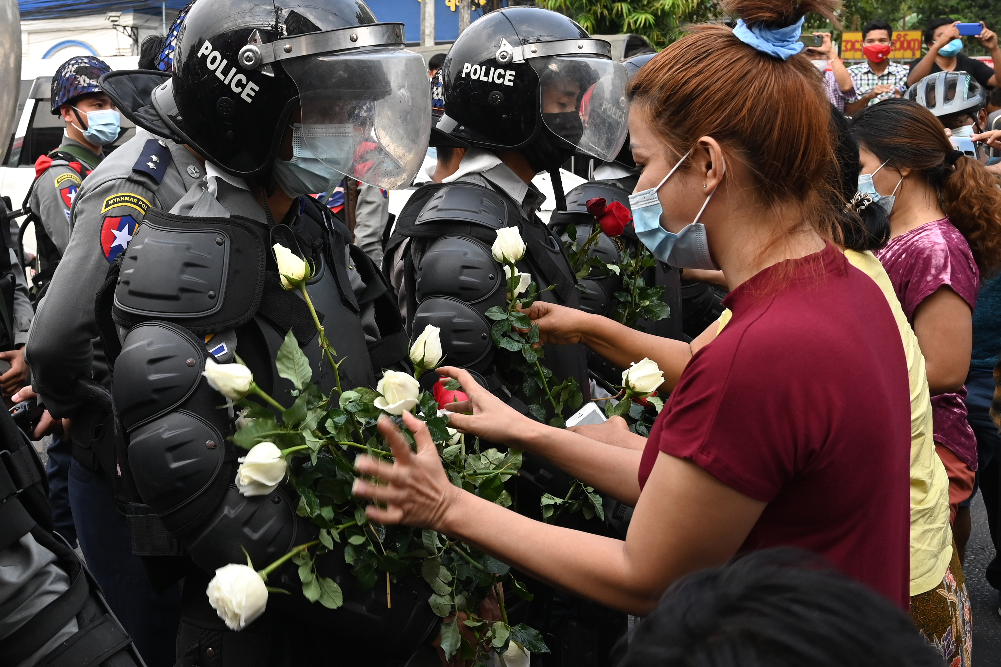 A protester gives flowers to a line of riot police during a demonstration against the military coup in Yangon on February 6, 2021