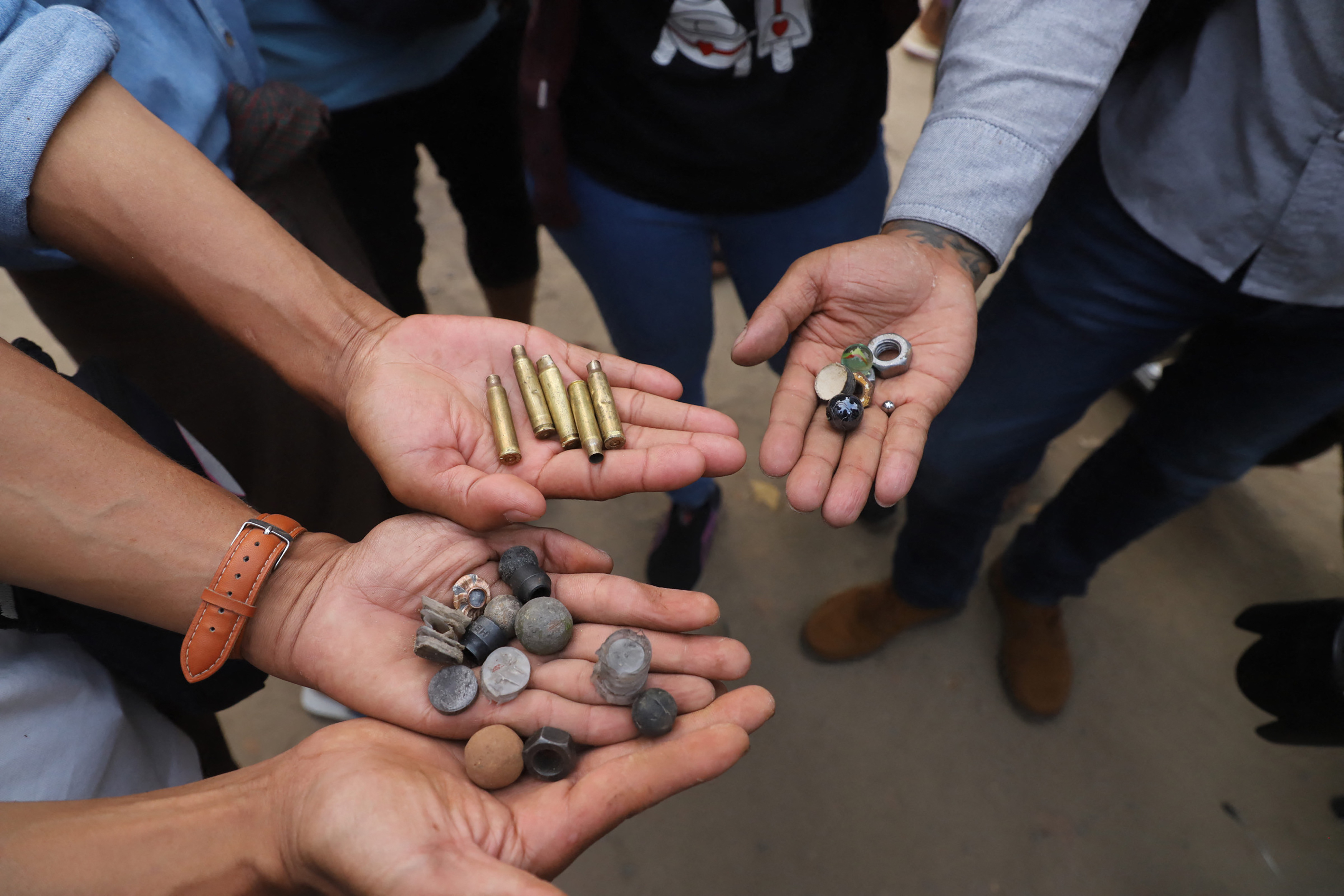 Protesters hold out bullet cartridges and ammunition for slingshots after security forces fired on demonstrators at a rally against the military coup in Mandalay on February 20, 2021.