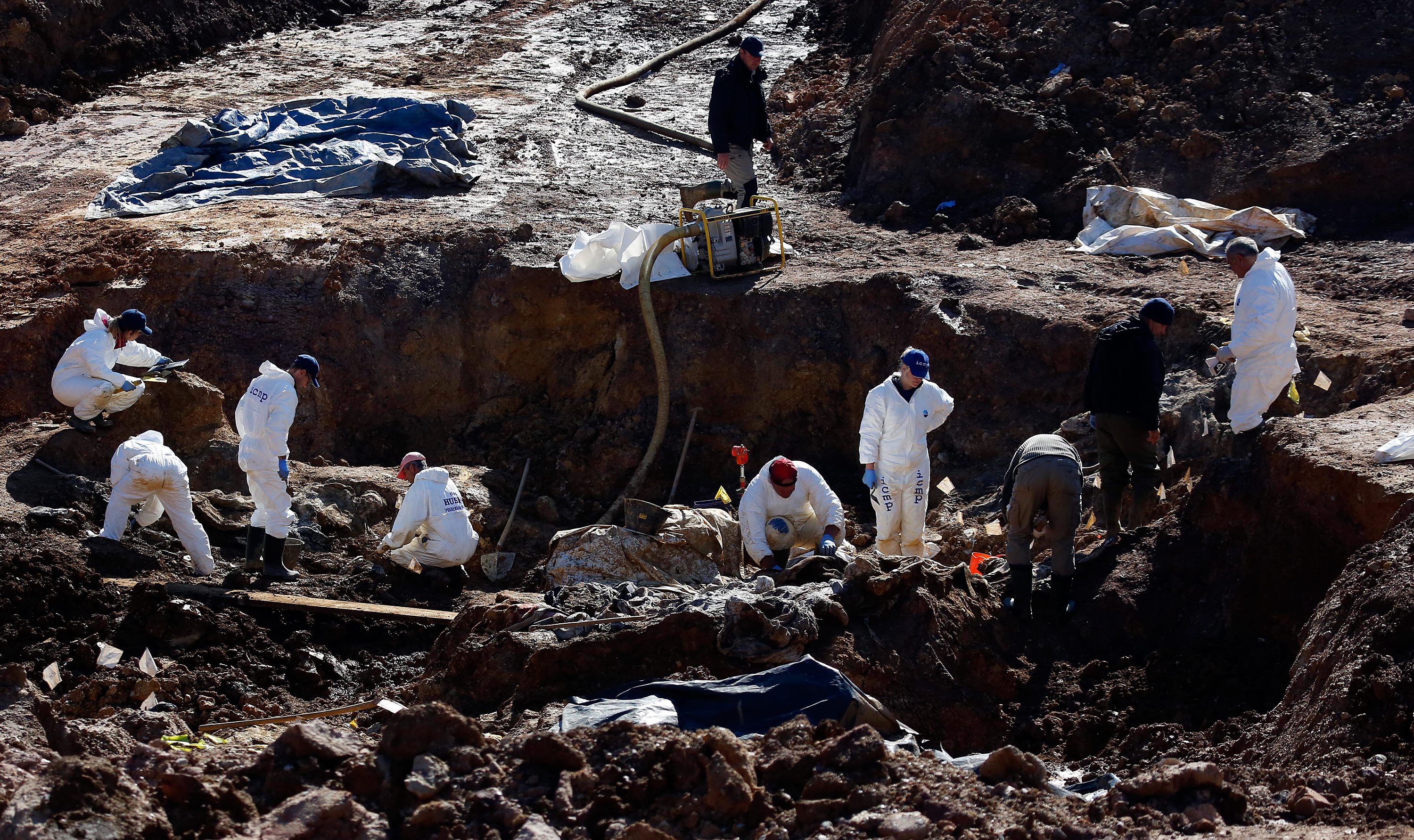 Forensic experts and workers search a mass grave in the village of Tomasica in western Bosnia on October 4, 2013. Experts found 94 body remains as they excavated a seven-metre deep trench