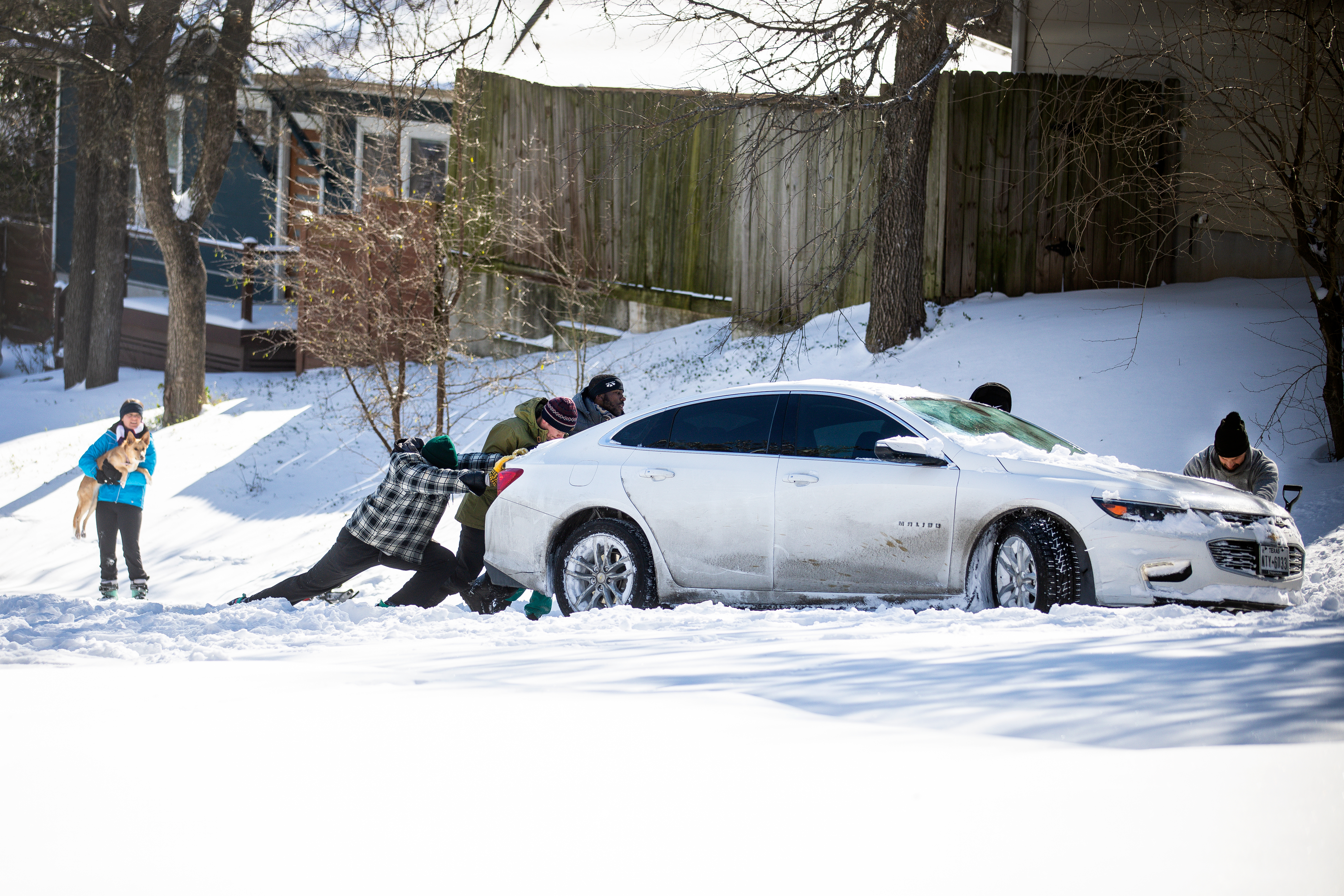 East Austin residents push a car out of the snow on February 15, 2021, in Austin, Texas