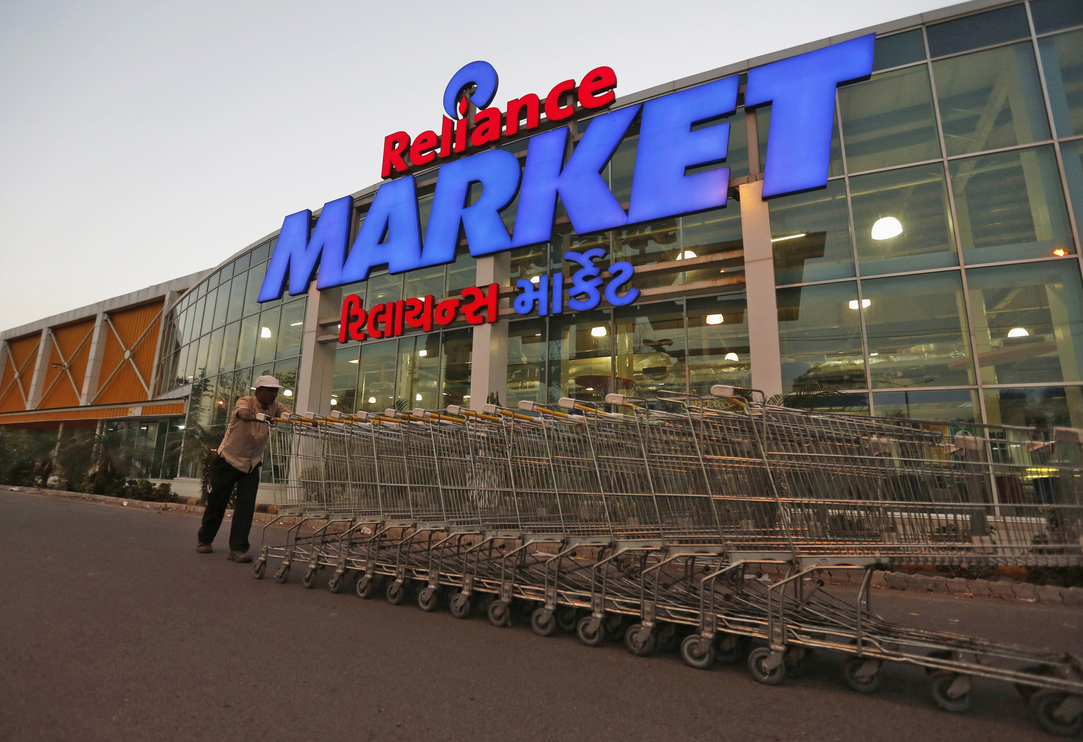 A man pushes grocery carts outside a Reliance Retail store