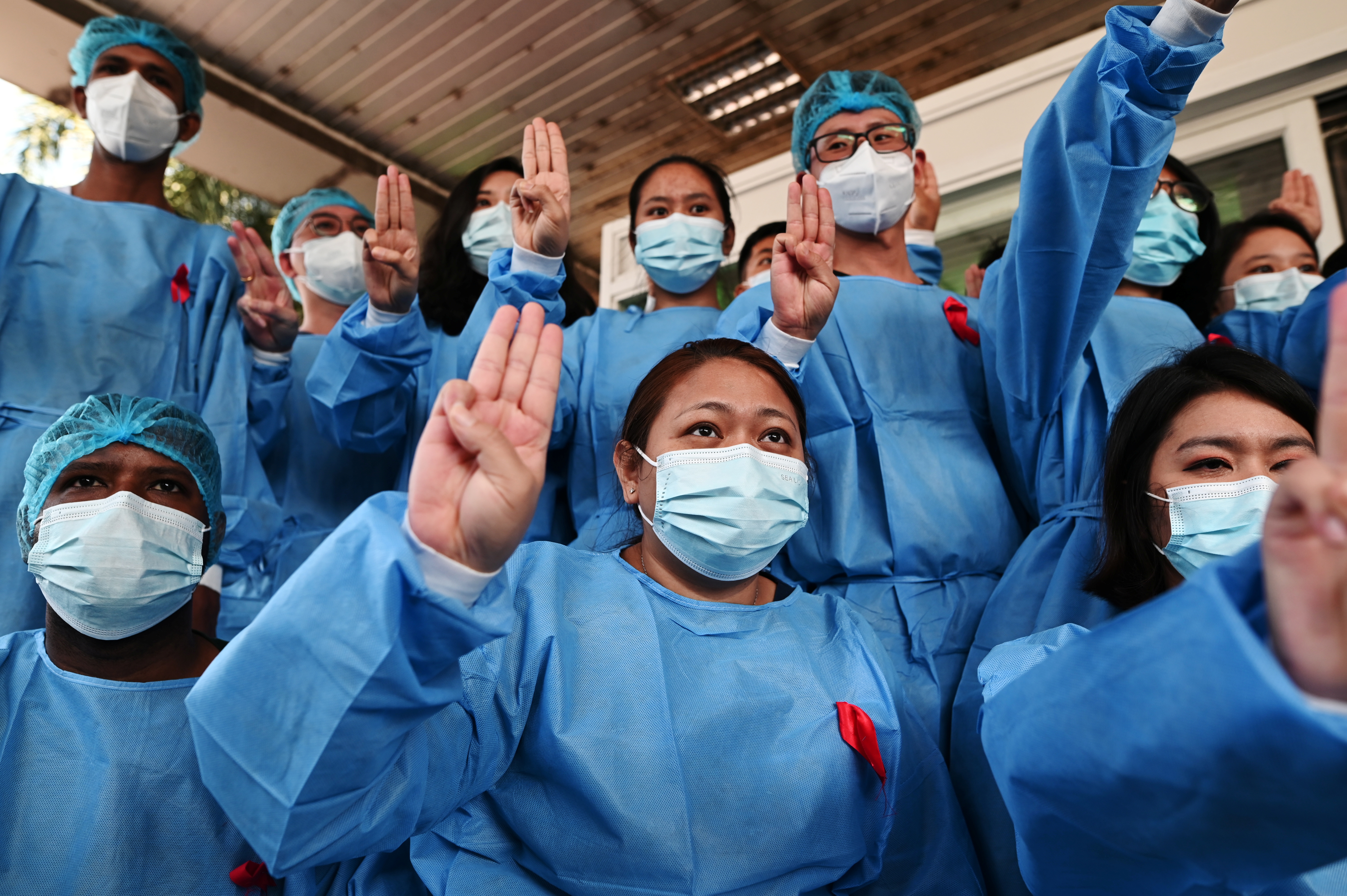 Medical workers wearing red ribbons pose during a protest against the coup that removed elected leader Aung San Suu Kyi, at Yangon General Hospital, in Yangon, Myanmar February 3, 2021