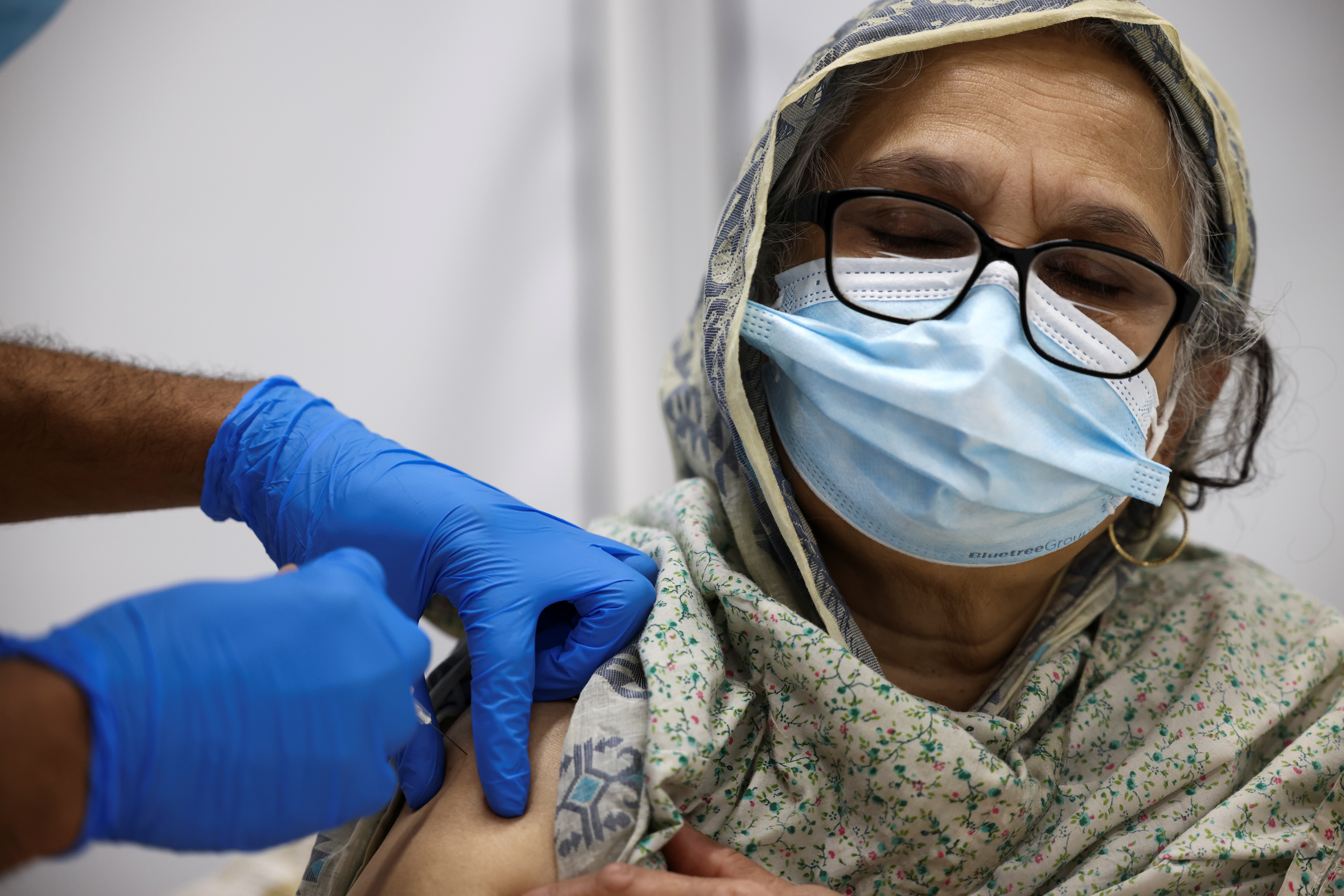 A woman gets the coronavirus vaccine, at a vaccination centre in Westfield Stratford City shopping centre, amid the outbreak of COVID-19, in London, UK [File: Henry Nicholls/Reuters]