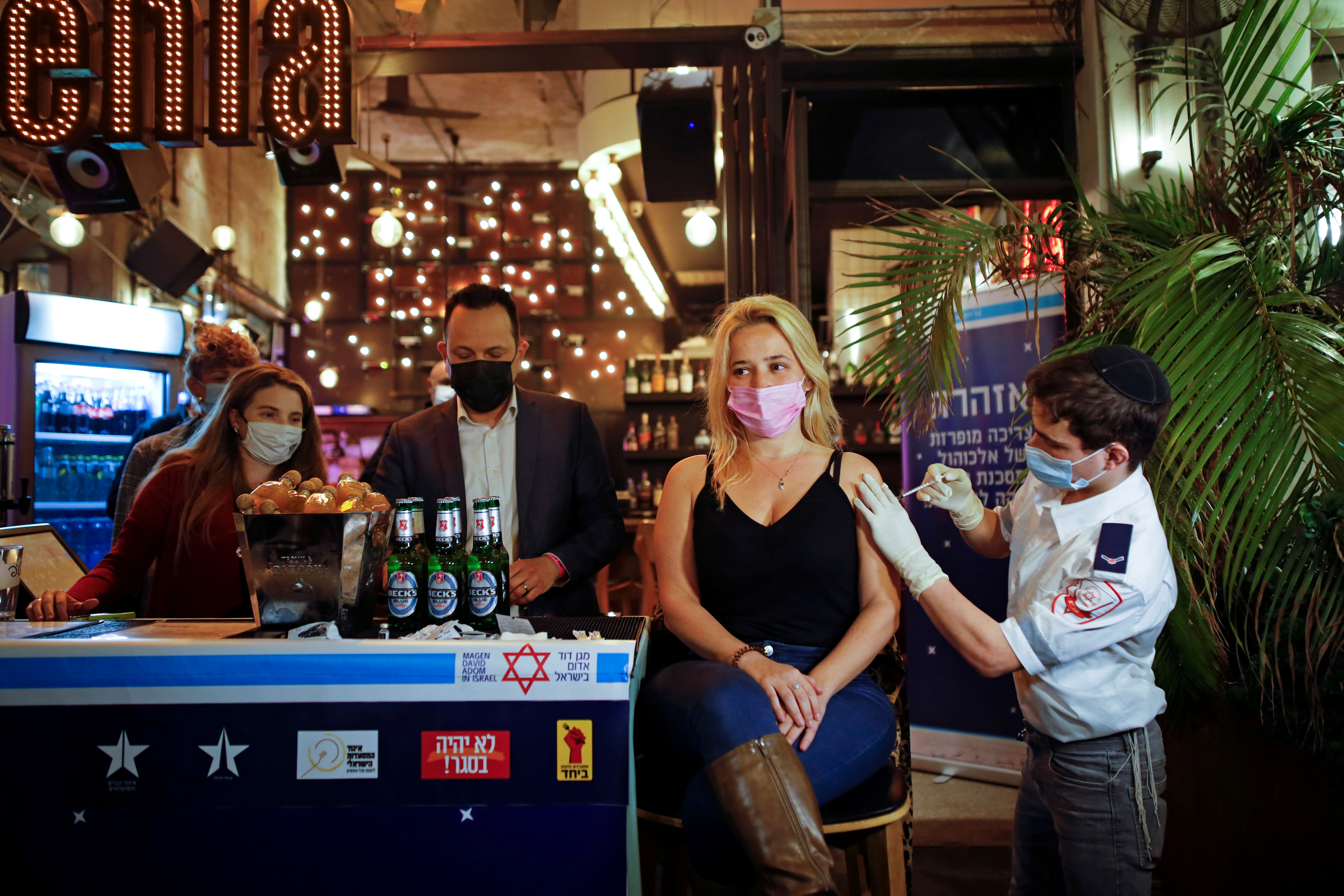 A woman receives a jab against the coronavirus as part of a Tel Aviv municipality initiative offering a free drink at a bar to residents getting the shot