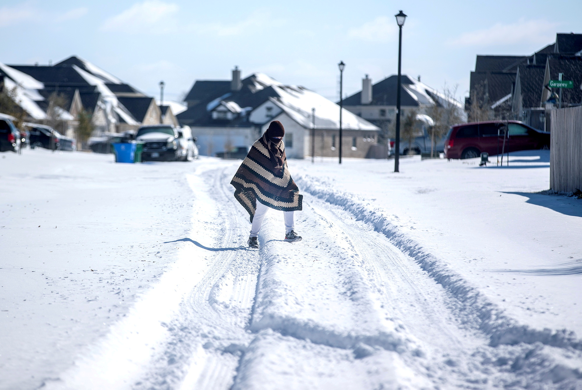 A man walks to his friend’s home in a neighbourhood without electricity as snow covers the BlackHawk neighbourhood in Pflugerville, Texas, on February 15, 2021