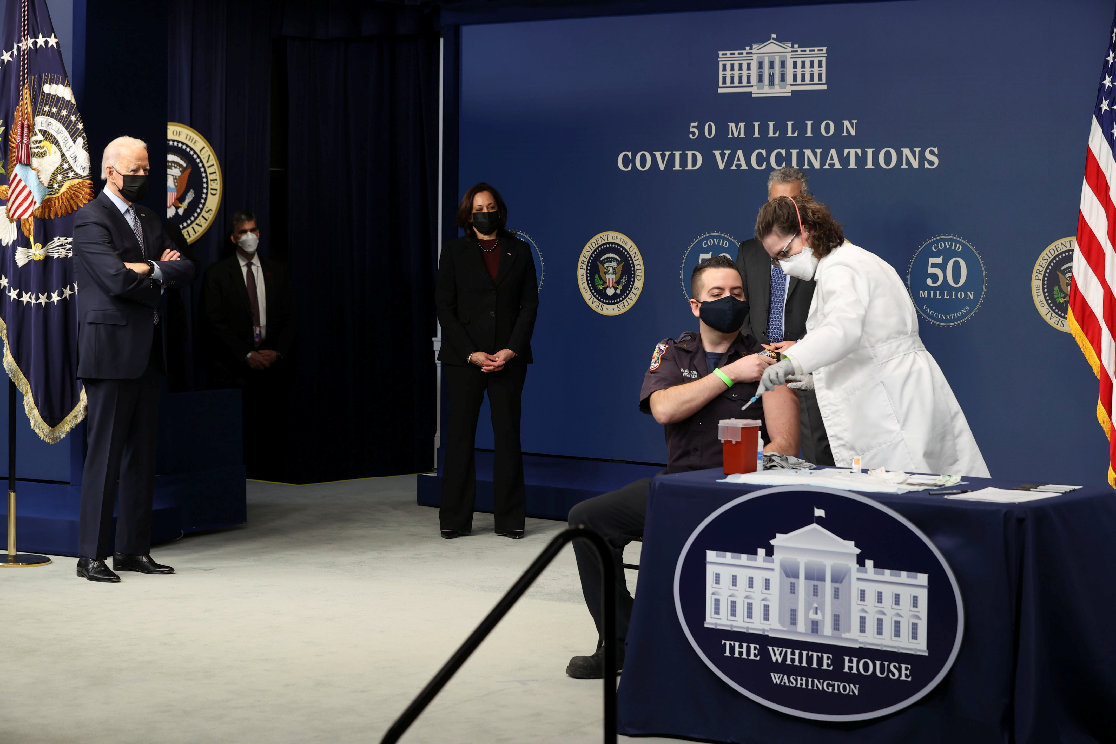 Washington, DC firefighter EMT Corey Hamilton receives a dose of the Pfizer vaccine during an event to commemorate the 50 millionth COVID-19 vaccination, in Washington