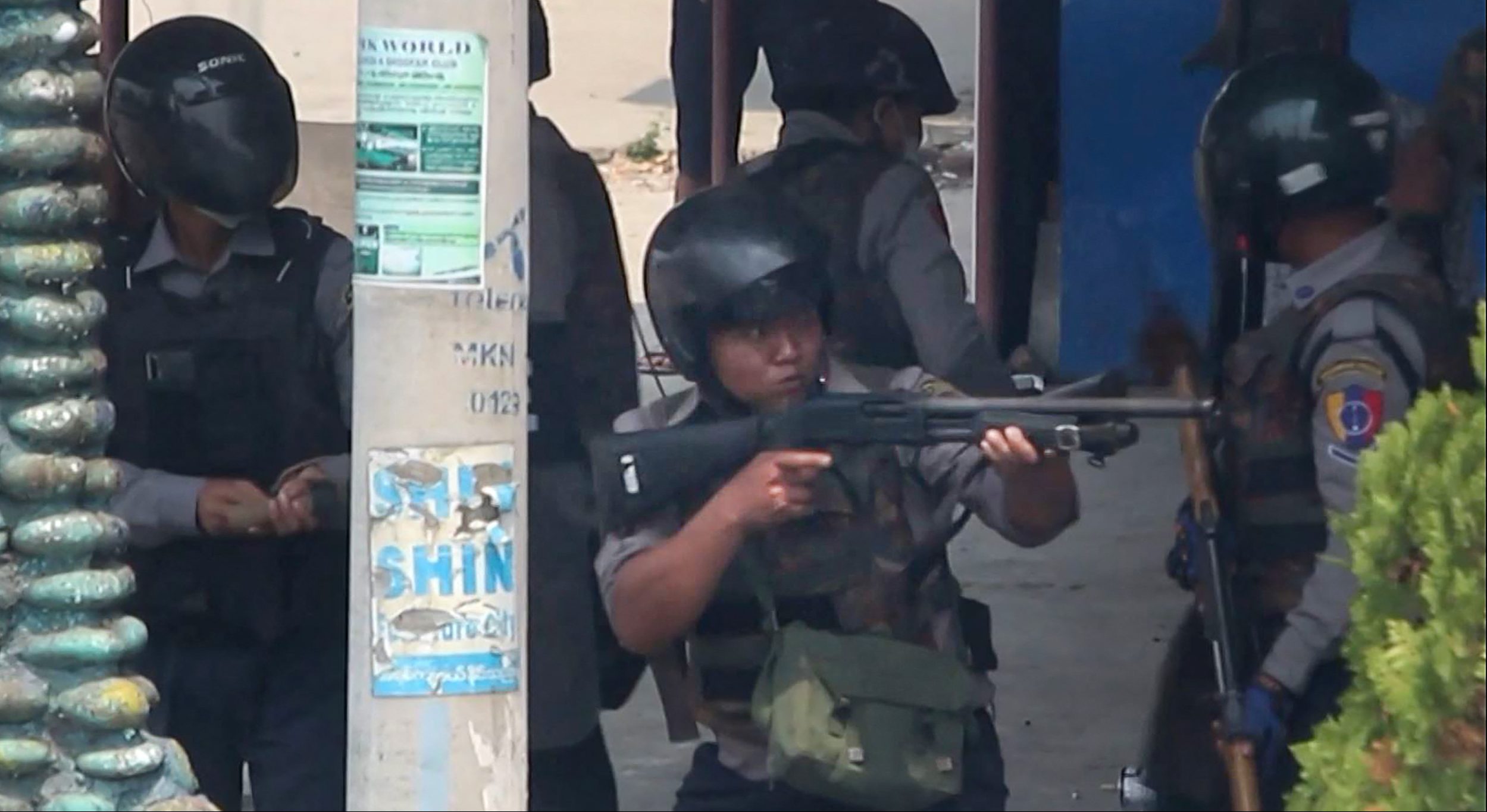 A policeman aims a gun at protesters in Myitkyina in Myanmar's Kachin state