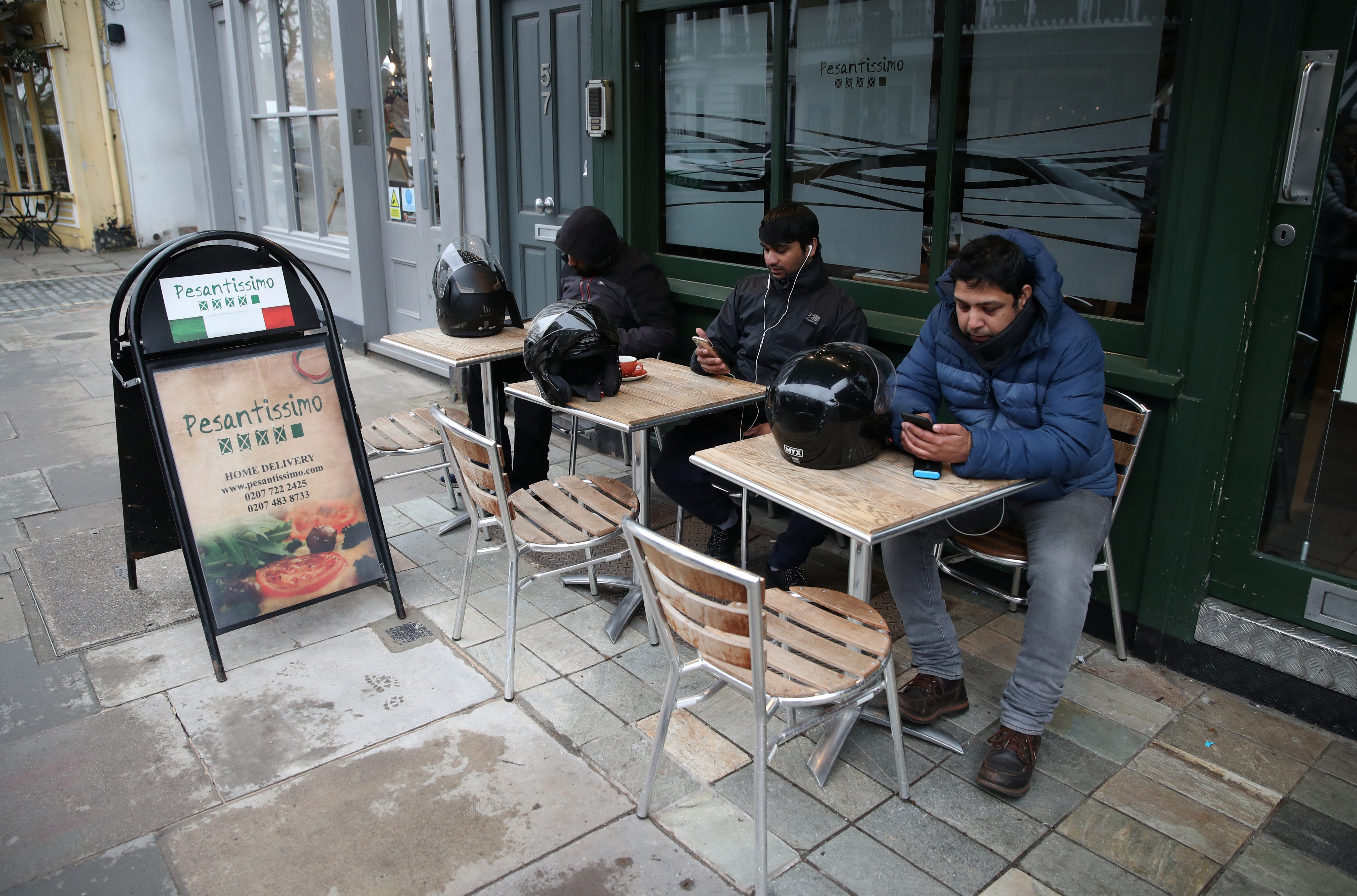 Food delivery drivers outside a restaurant waiting for work near Primrose Hill in London as the spread of the coronavirus disease continues [File:Peter Cziborra/Reuters]