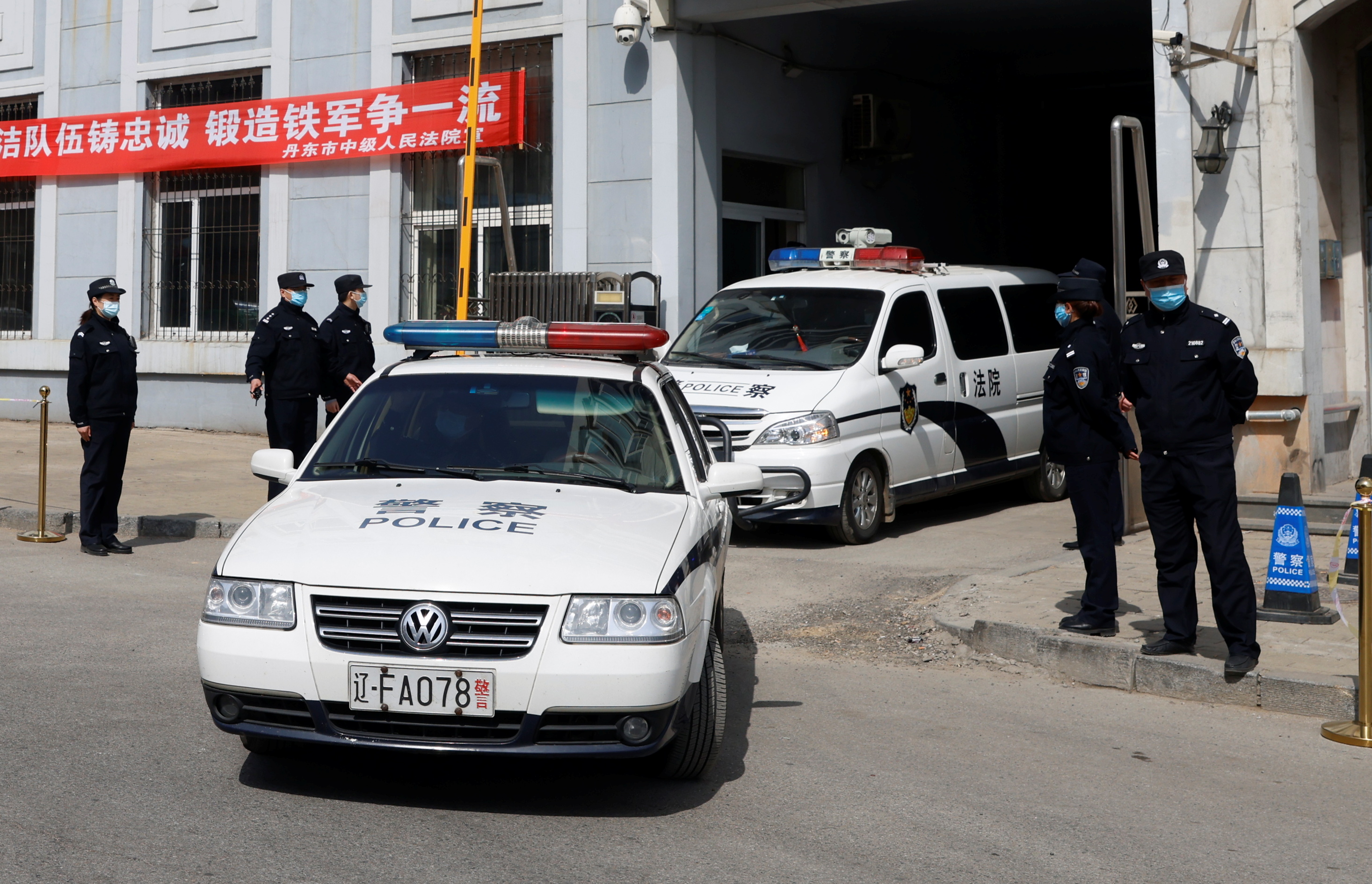 Police vehicles exit the Intermediate People’s Court in Dandong where Michael Spavor, a Canadian detained by China in December 2018 and later accused of espionage, stood trial on Friday
