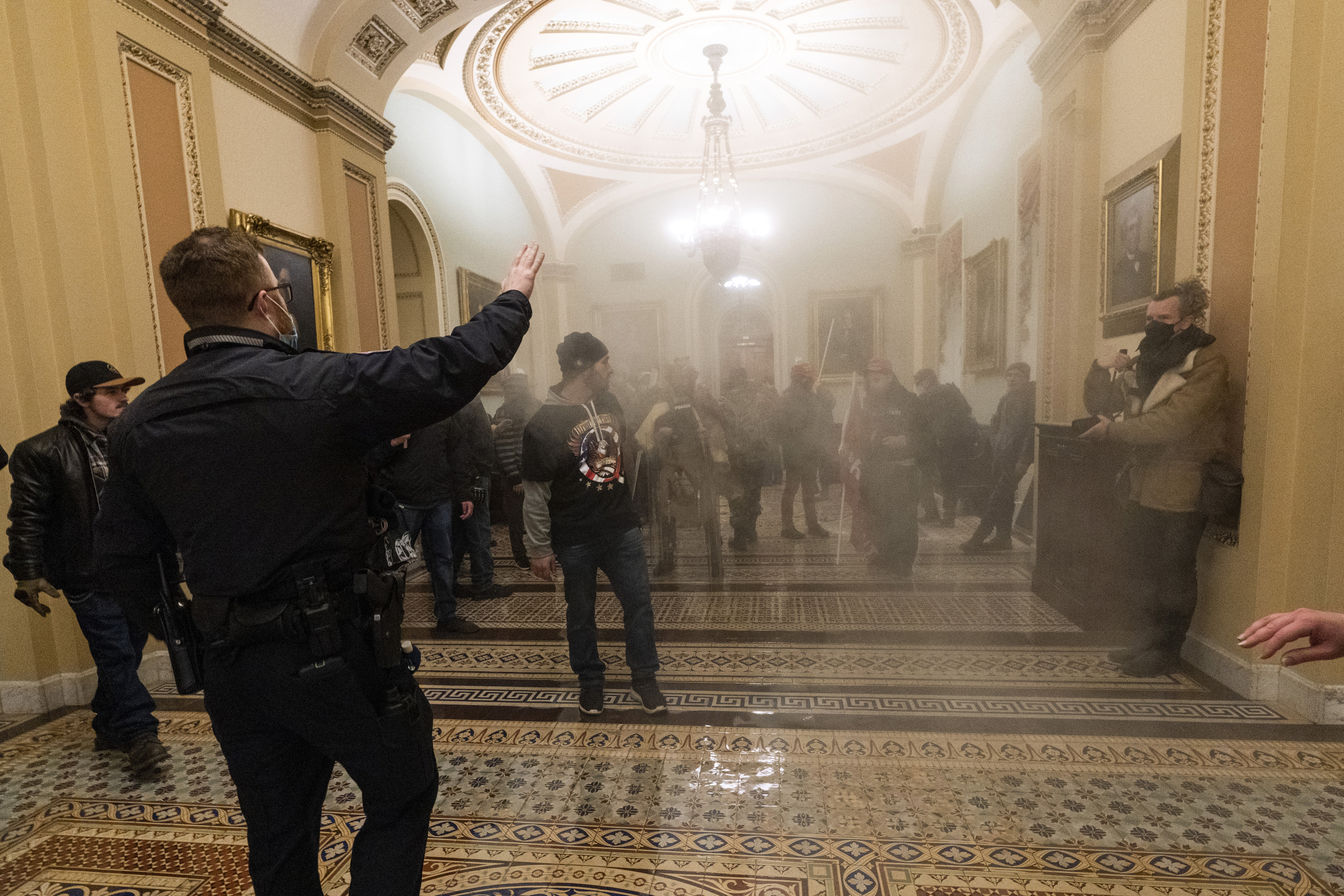 Smoke fills the walkway outside the Senate Chamber as rioters are confronted by US Capitol Police officers inside the Capitol, on January 6, 2021