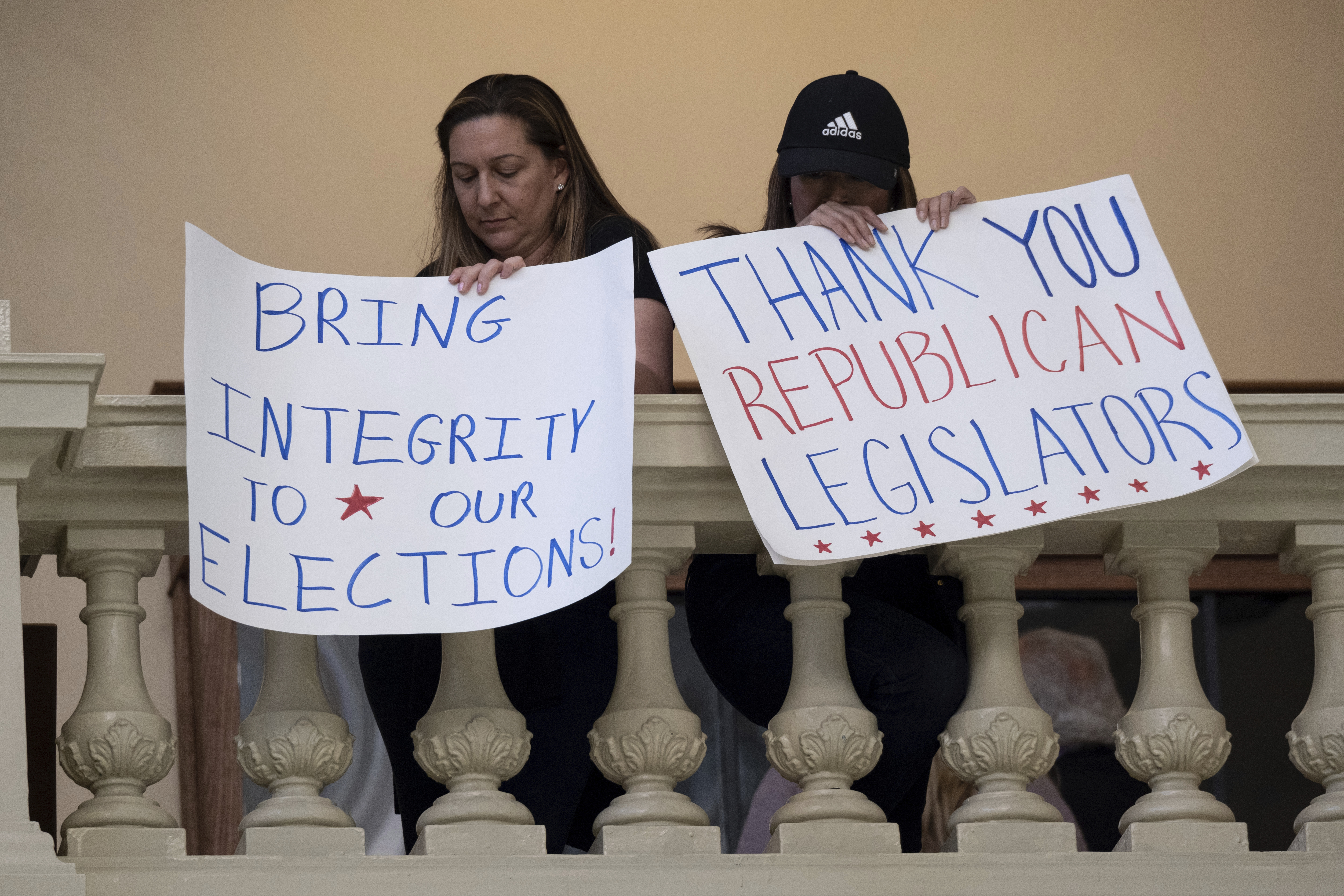 Protesters in favor of changes to Georgia’s voting laws hold signs inside the State Capitol in Atlanta, as the Legislature met to pass a new law in 2021 that civil rights leaders call restrictive