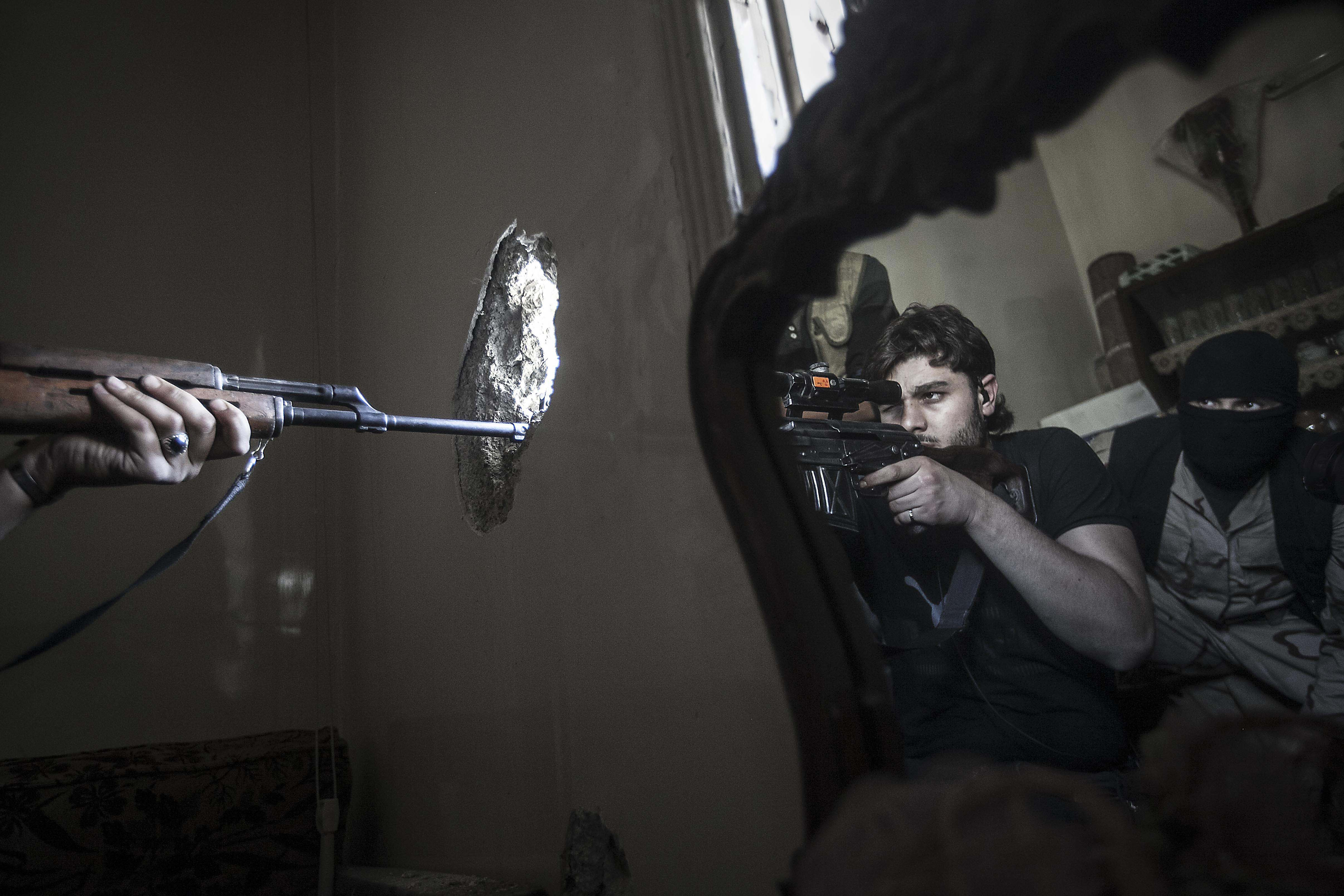 Ali aims at a Syrian army position, as he and another rebel fighter are reflected in a mirror inside a residential building in the Jedida district of Aleppo, Syria, on October 29, 2012 [Narciso Contreras]