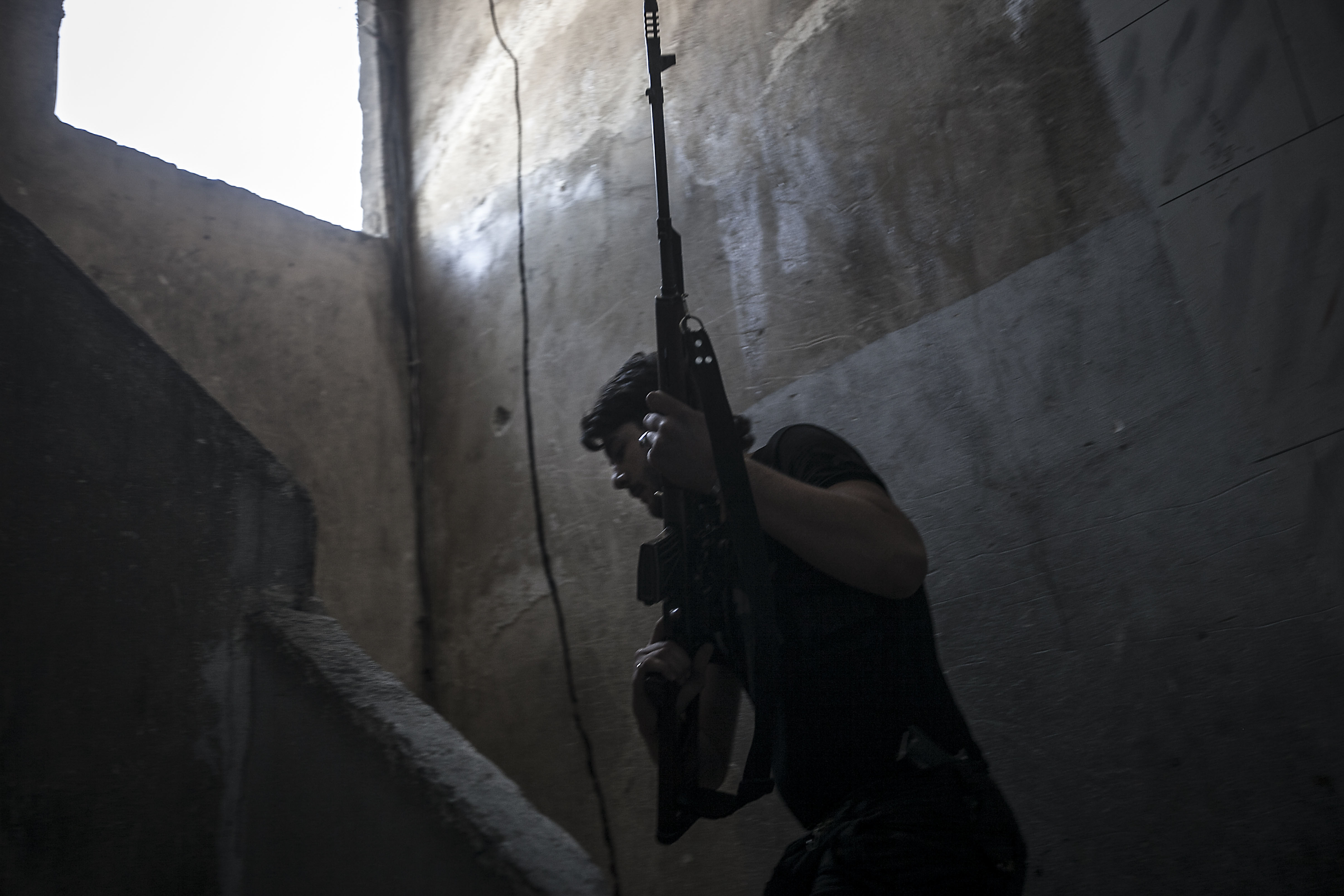 Ali sneaks through buildings to target Syrian army positions in the nearby Castel Harami battlefield in the Jdeide district of Aleppo, Syria, on October 29, 2012 [Narciso Contreras]