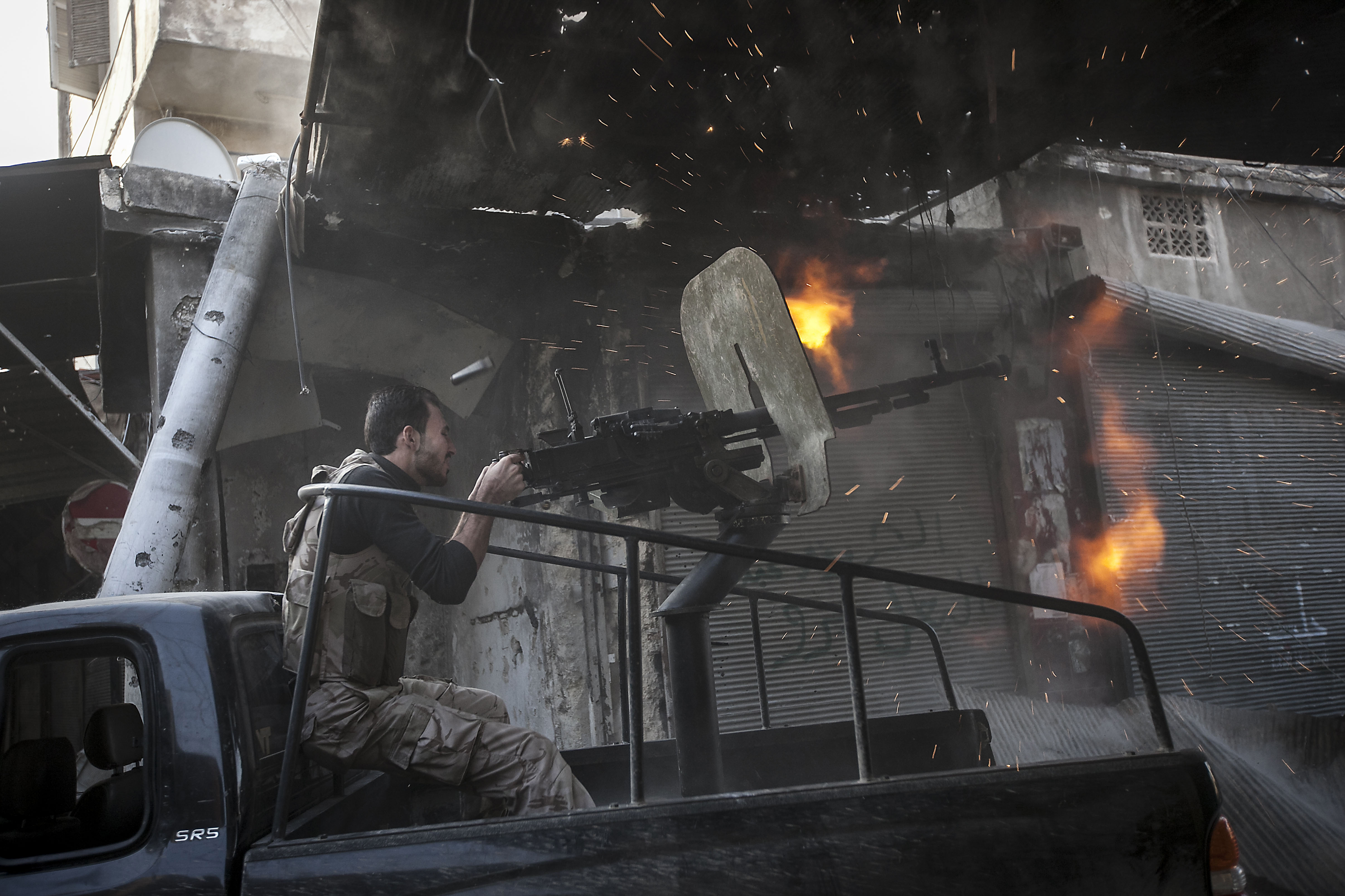 A rebel fighter fires a gun towards a building where Syrian troops loyal to President Bashar al-Assad were hiding, while they attempted to gain terrain against the rebels during heavy clashes in the Jedida district of Aleppo, Syria, on November 4, 2012 [Narciso Contreras]