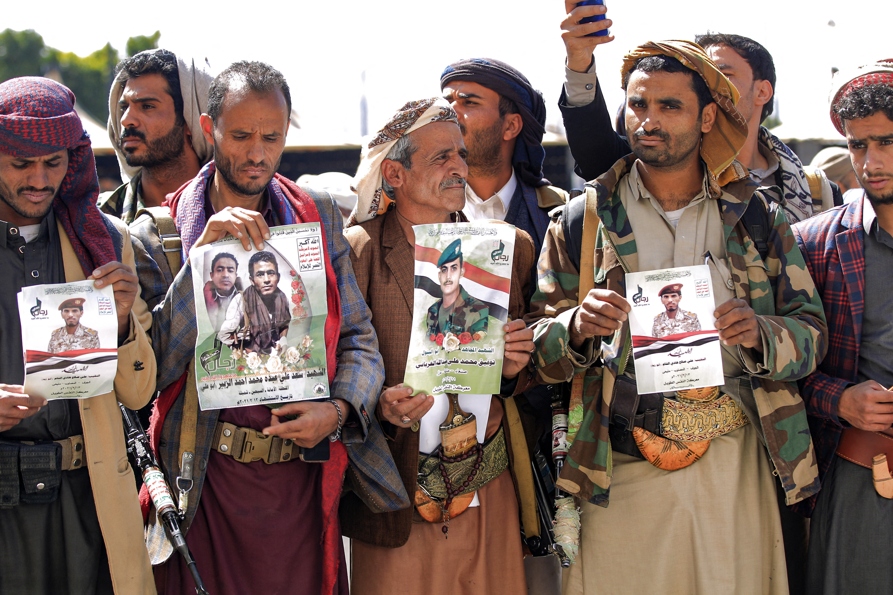 Fighters loyal to the Houthis hold up posters with the portraits of fallen comrades killed in recent battles, during a mass funeral for them at al-Saleh Mosque in Yemen's capital Sanaa on February 16, 2021 [File: AFP/ Mohammed Huwais]