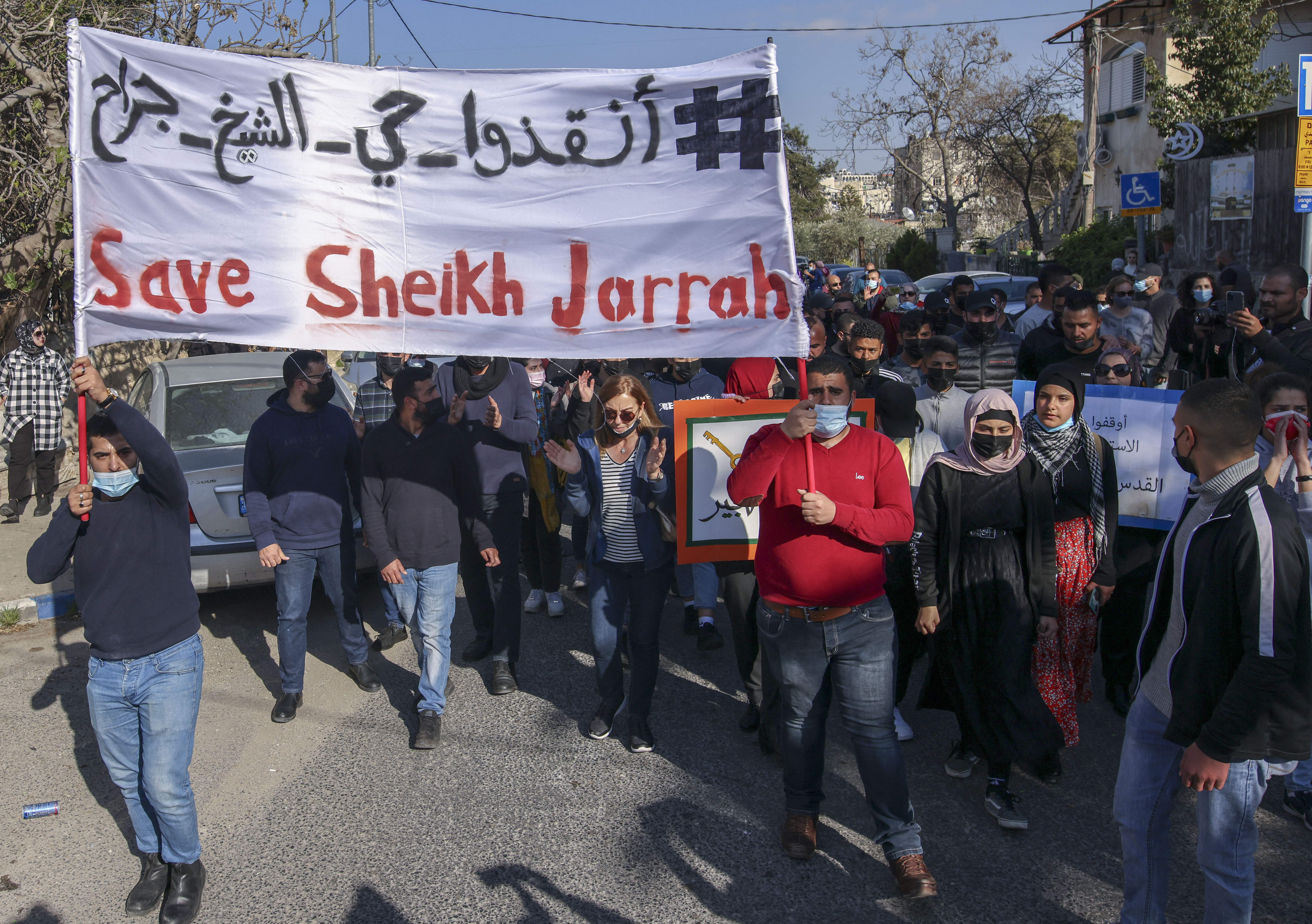 Palestinian, Israeli, and foreign activists lift banners and placards during a demonstration against Israeli occupation and settlement activity in Sheikh Jarrah