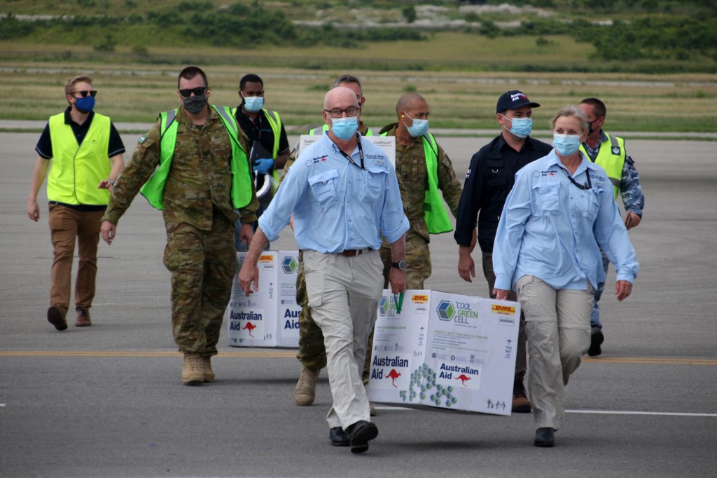 Australian officials carry boxes containing some 8,000 initial doses of the AstraZeneca vaccine following their arrival at the Port Moresby international airport last March