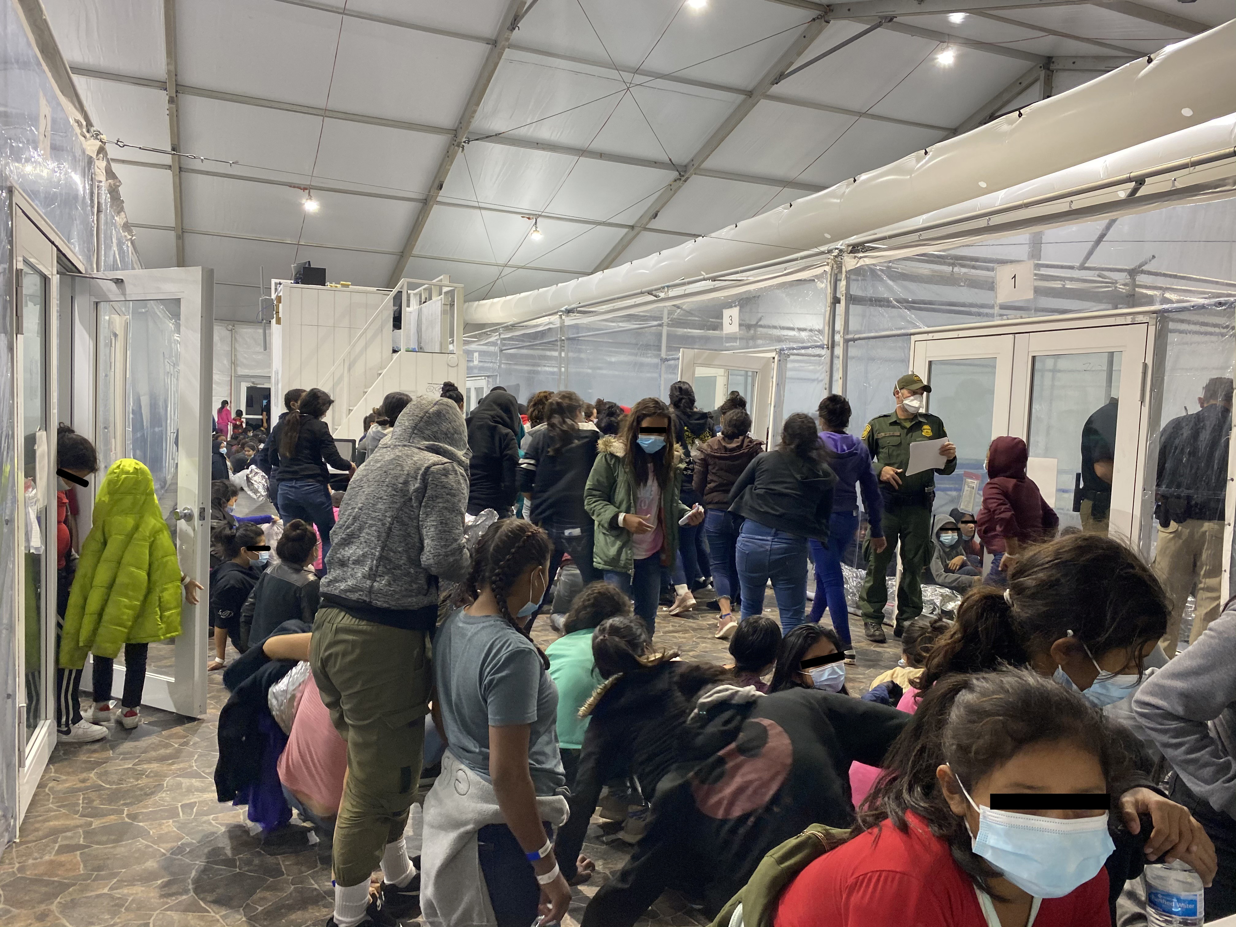 Migrants crowd a room with walls of plastic sheeting at a Customs and Border Protection processing centre in Texas [Handout via Reuters]