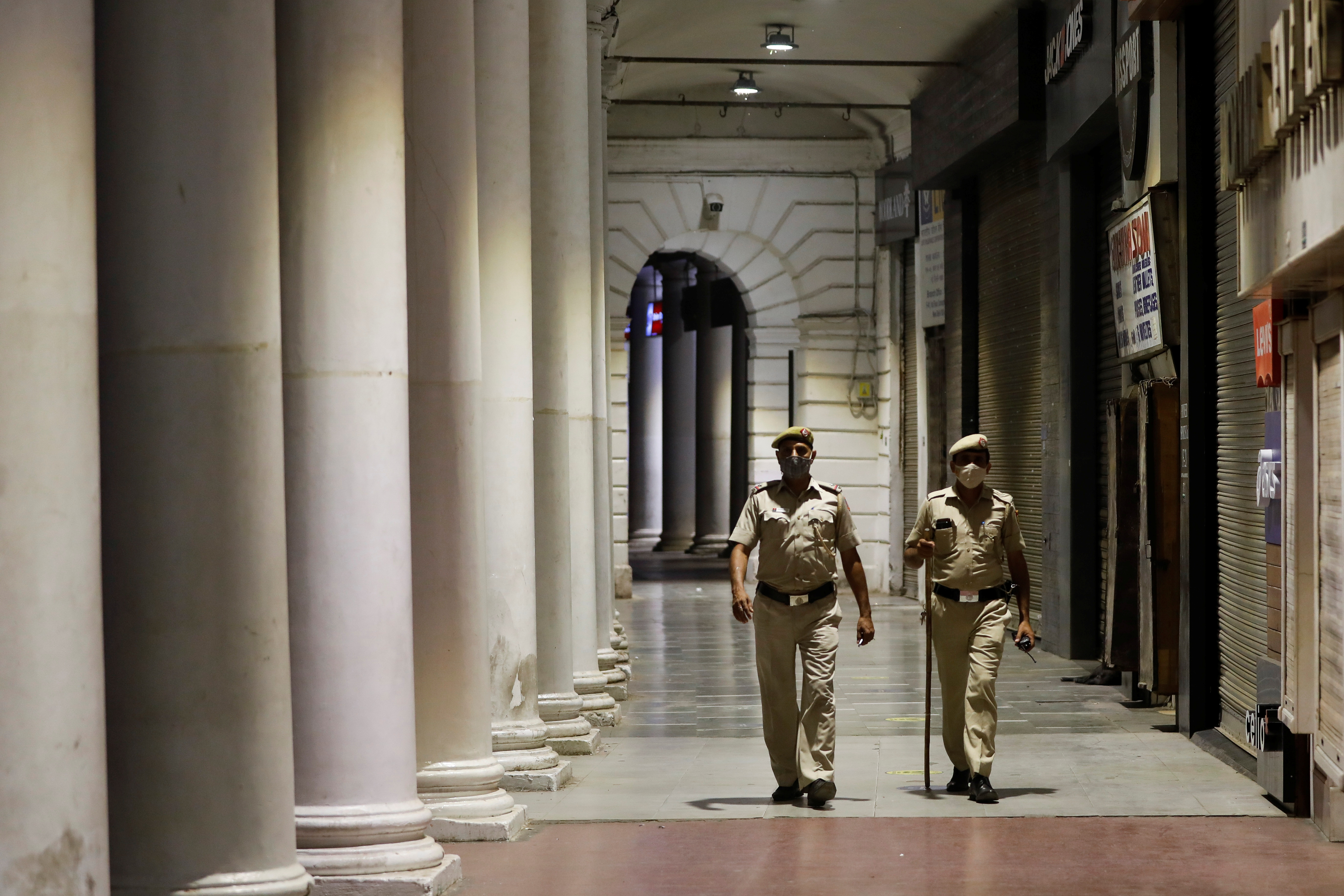 Police officers patrol in front of closed shops at a market area during a curfew to limit the spread of the coronavirus disease in New Delhi