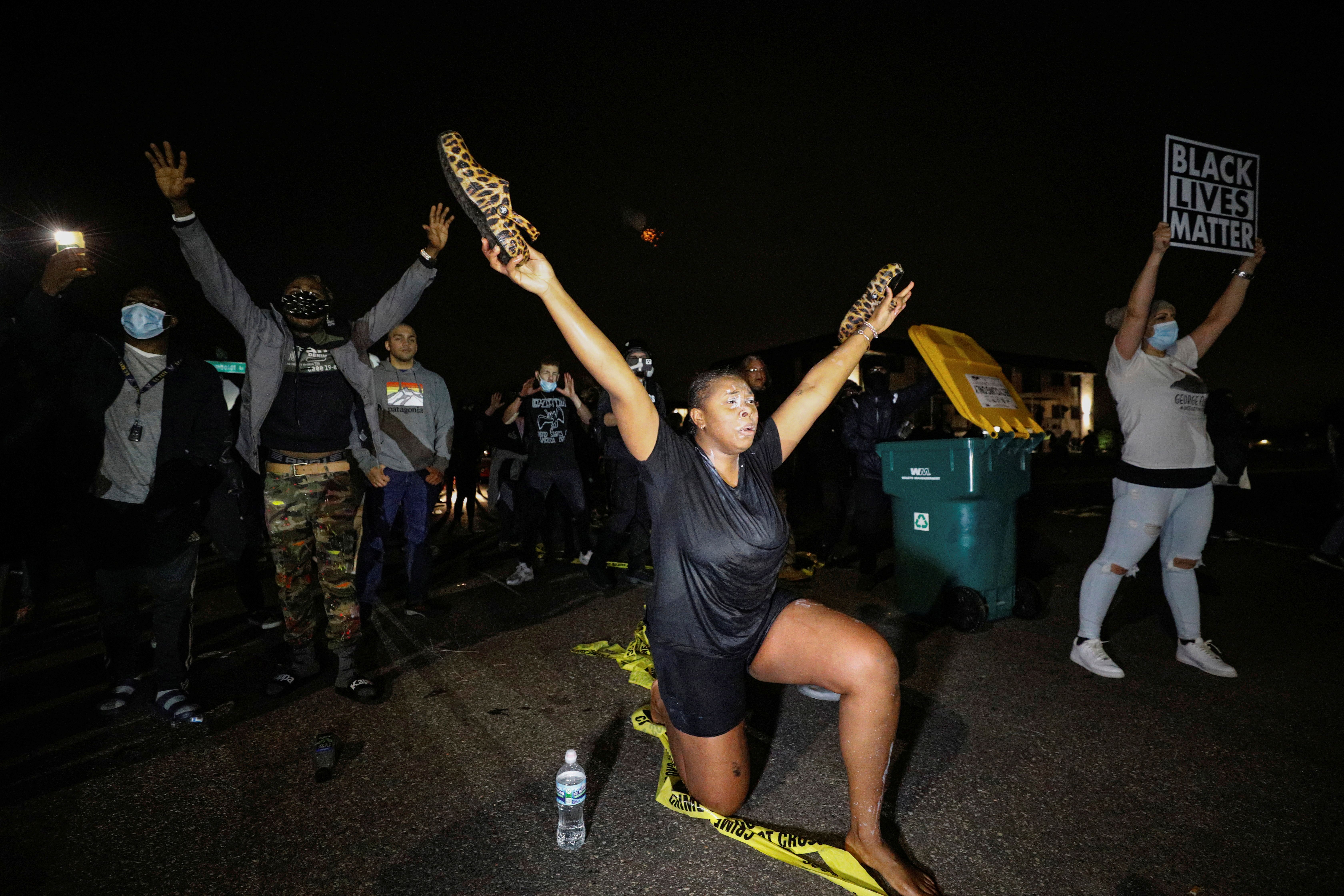 A woman who was tear-gassed while confronting police raises her arms outside Brooklyn Center Police Department after police allegedly shot and killed Daunte Wright, in Brooklyn Center, Minnesota, the US