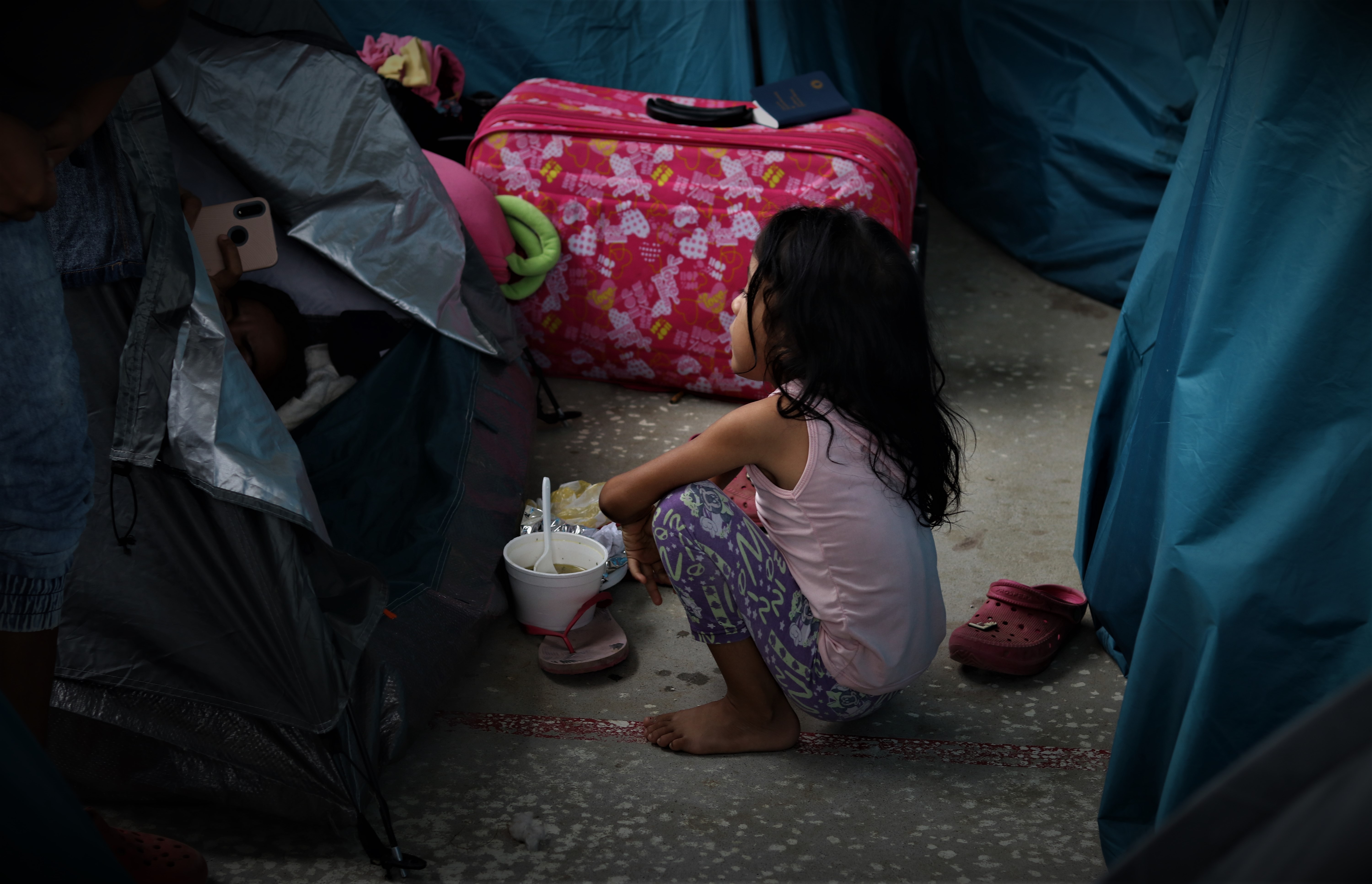 A young child eats outside a tent in one of the settlements About 1,000 children make up the 5,000 people who fled to Arauquita