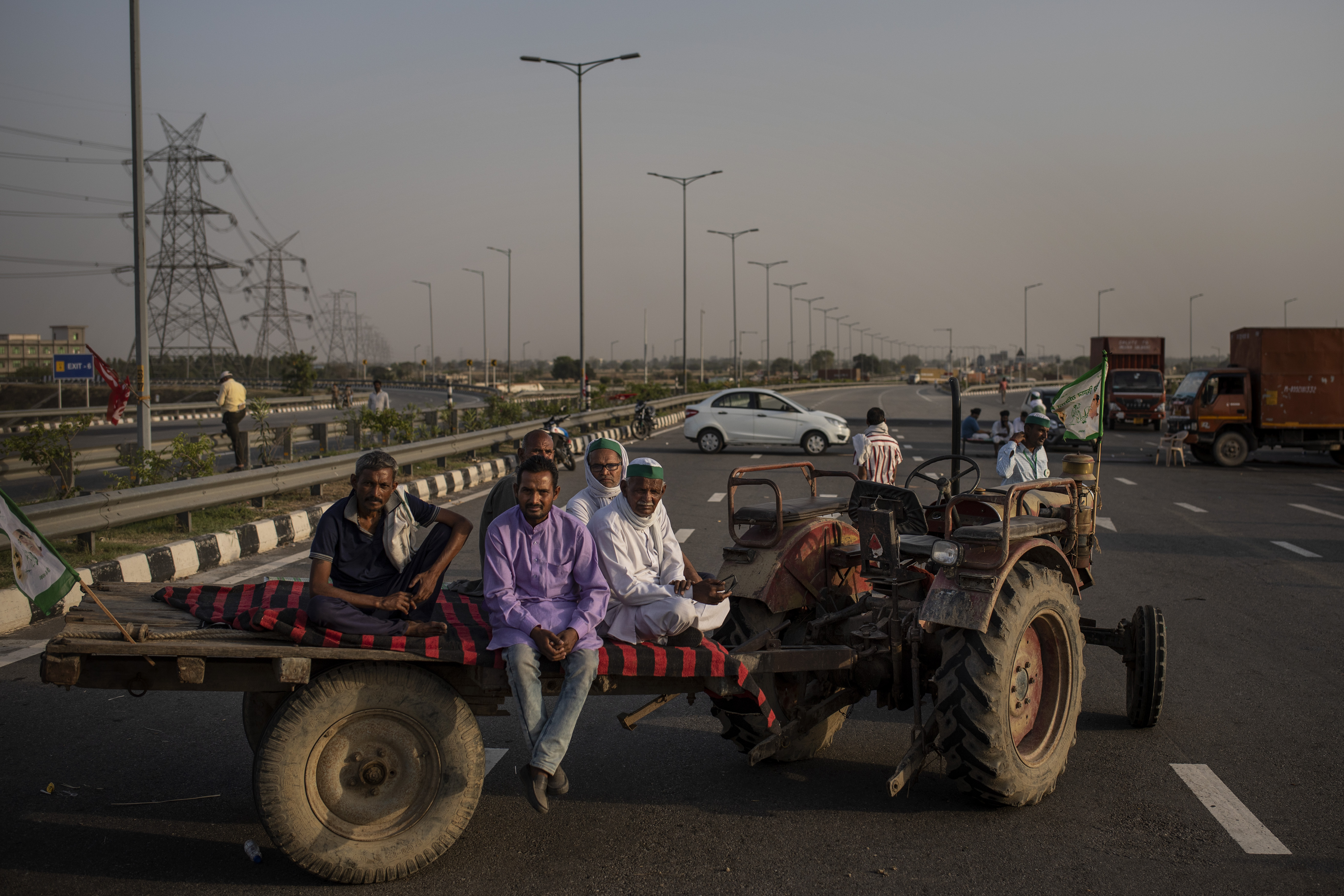 Farmers sit in a tractor-trailer during a 24-hour blockade of a major expressway as part of their ongoing protests against new farm laws in Dasna, India