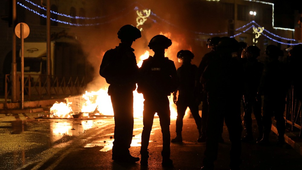 Israeli police officers stand next to a burning barricade during clashes with Palestinians